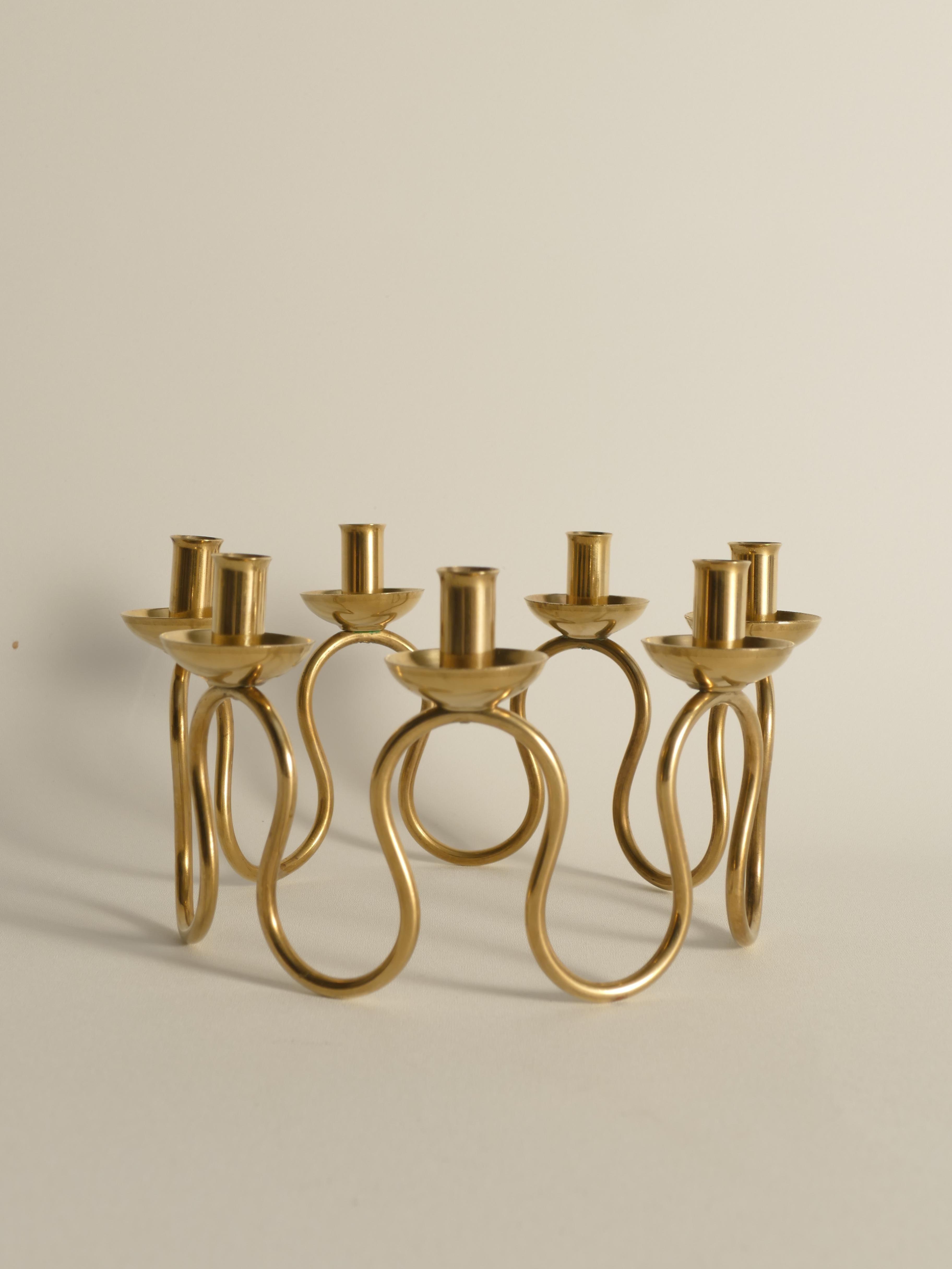 Stunning candelabra in brass by Lars Holmström, Arvika for Firma Svenskt Tenn. This candelabra features seven holders and a curved organic form. One candle cup is slightly loose, but it's not noticeable. It has been thoroughly cleaned, with no wax