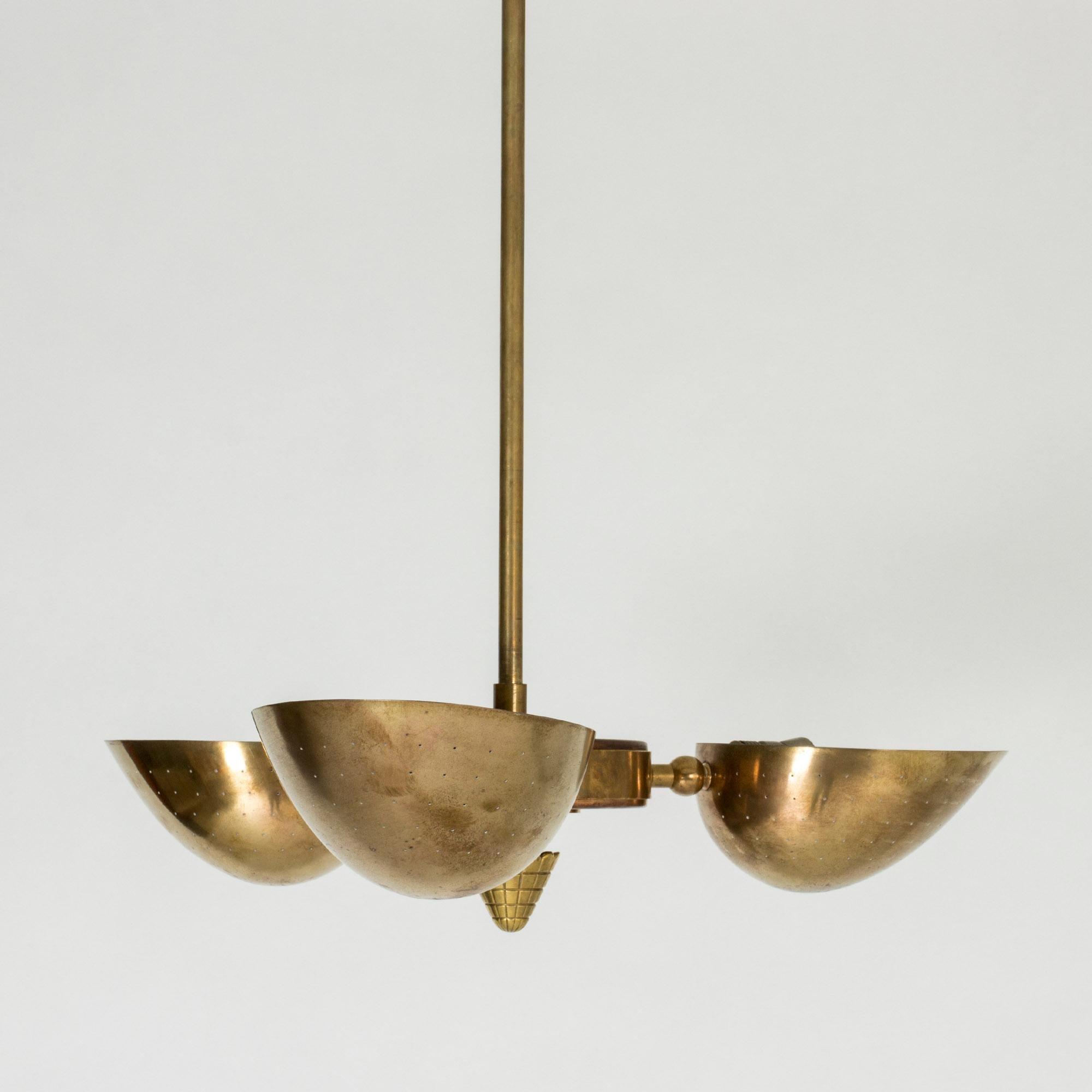 Beautiful brass chandelier from the Swedish Modern period. Striking, clean lines and great patina. The three shades perforated with tiny holes that lets the light out in a starry sky pattern from below.