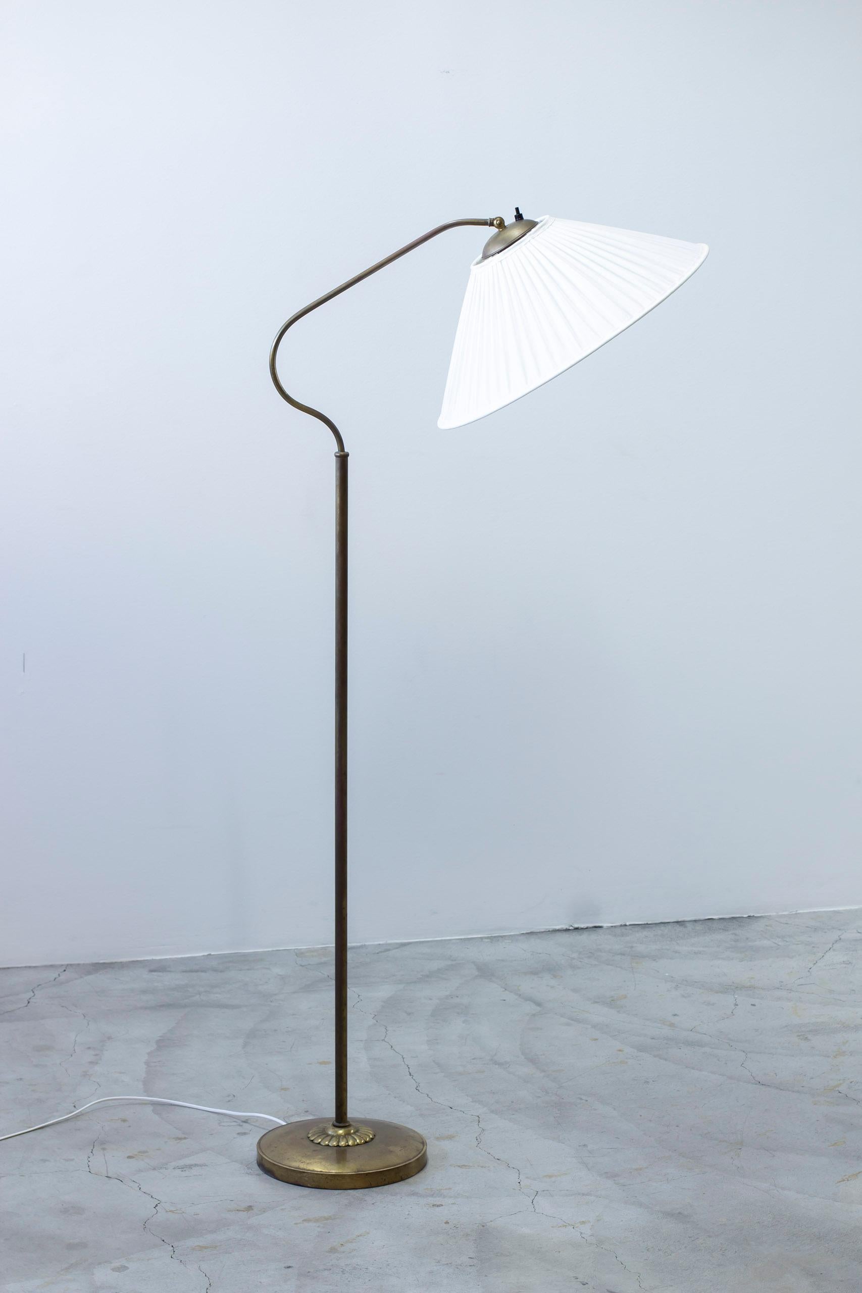 Lampada da terra disegnata da Bertil Brisborg. Prodotto dalla Nordiska Kompaniet negli anni 1940-50. Realizzata in ottone con un grande paralume rivestito in tessuto di cotone chintz con un aspetto a pieghe singole. L'interruttore della luce sulla