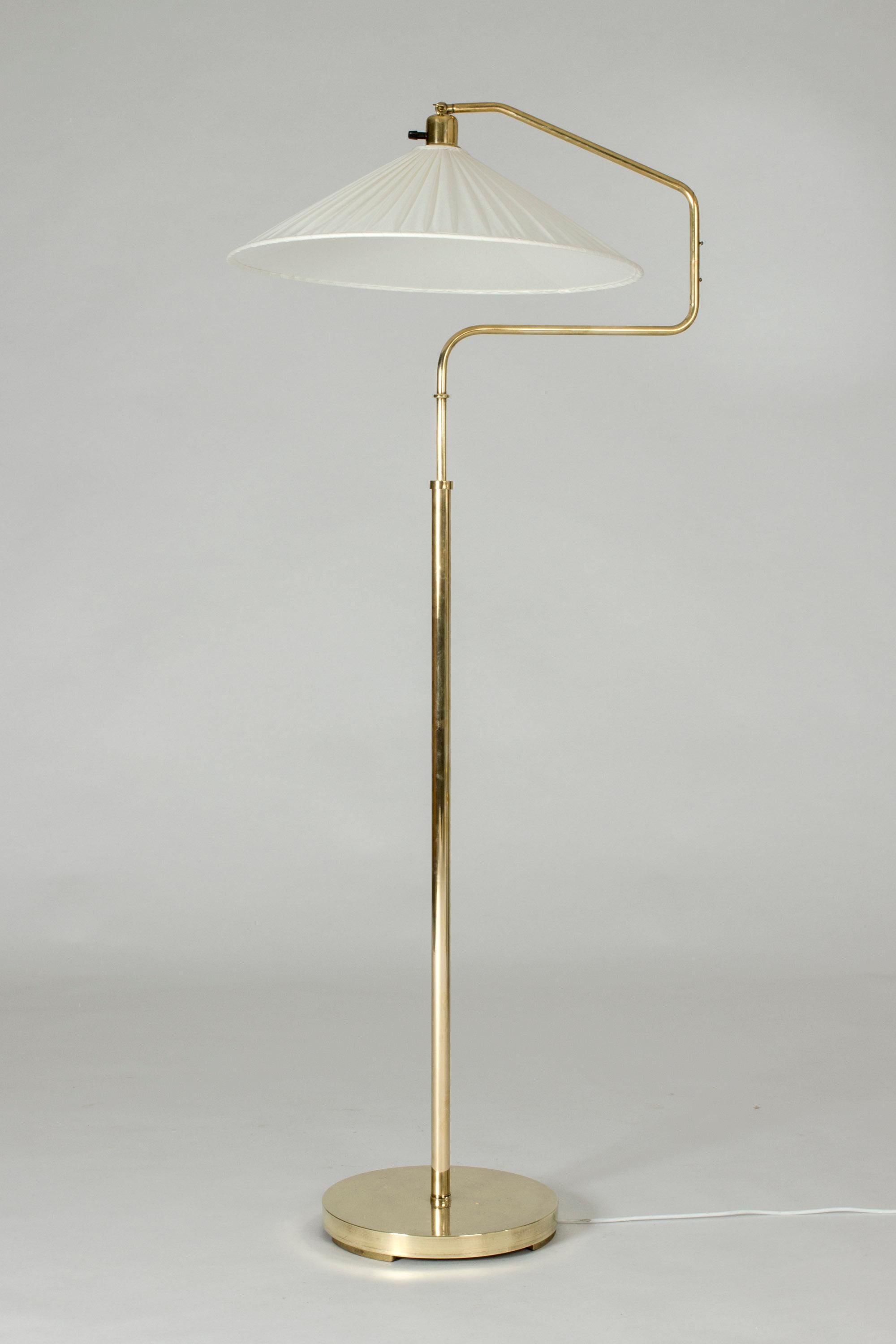 Swedish modern brass floor lamp with a long neck that can extend and elevate the shade in different directions. Adjustable height. Wide brass base with a solid weight.