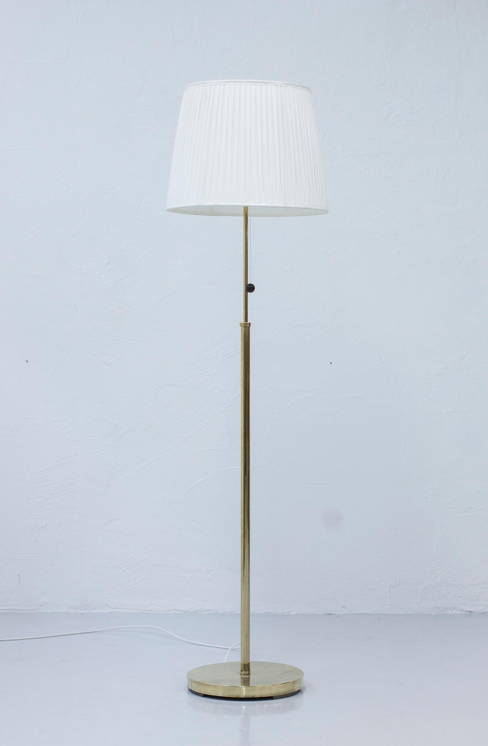 Swedish Modern floor lamp in the manner of Josef Frank, made during the 1940-50s. Polished brass and hand sewn, pleated lamp shade in off white chintz fabric. Chord light switch with rosewood ball as the pull handle. Very good vintage condition with