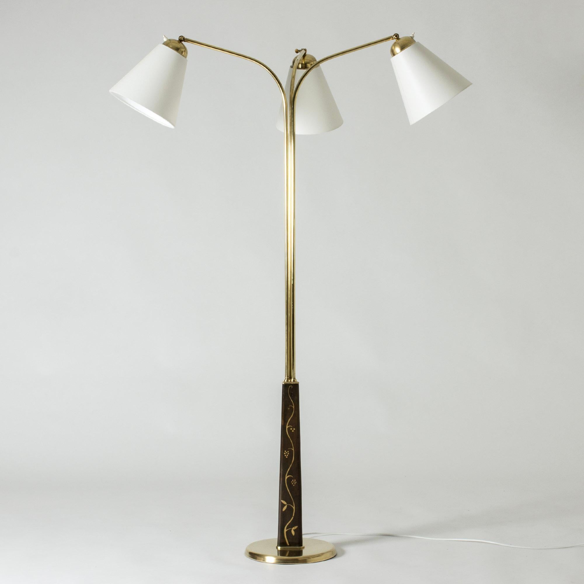 Elegant Swedish Modern floor lamp by Tor Wolfenstein, made from brass with three lamp shades. Tapering wooden base with painted decor of flowers and leaves. The direction of the lamp shades can be adjusted.