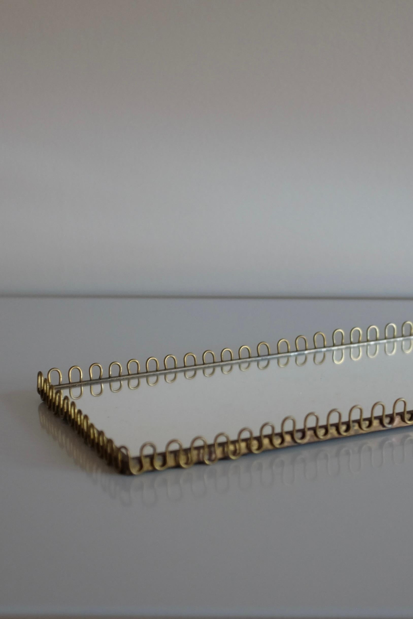 Charming Swedish Mid-Century Mirror tray in brass and glass with an oval filigree design. Design resembles similar made by Svenskt Tenn during the 1940/50s. In good vintage condition with patina to the brass and the glass.

Size: L 12 in x W 5.5 in
