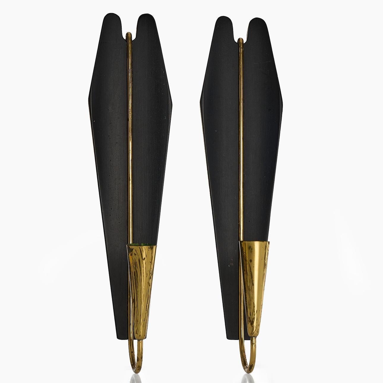 Una coppia di applique svedesi della metà del secolo scorso, disegnate da Gösta Ahrneberg negli anni '50, splendidamente scolpite.
Questi eleganti pezzi combinano il legno massiccio laccato nero con bracci a candela in ottone curvato, dando vita a