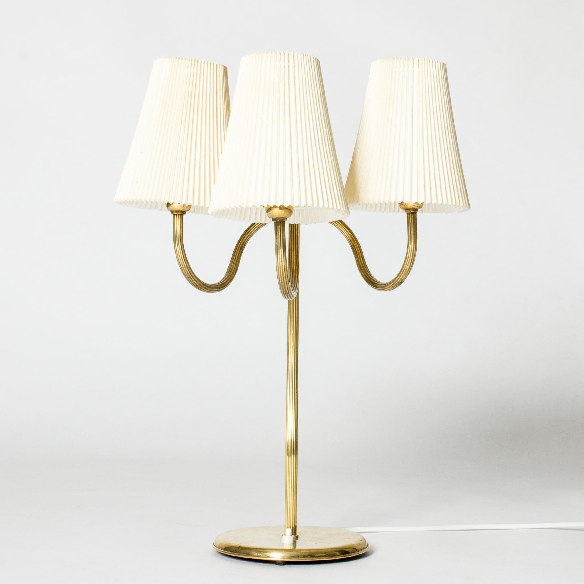 Beautiful Swedish Modern table lamp, made from brass in a slender, sculptural design with three twirled arms. Embossed stripes, three original wreathed shades.