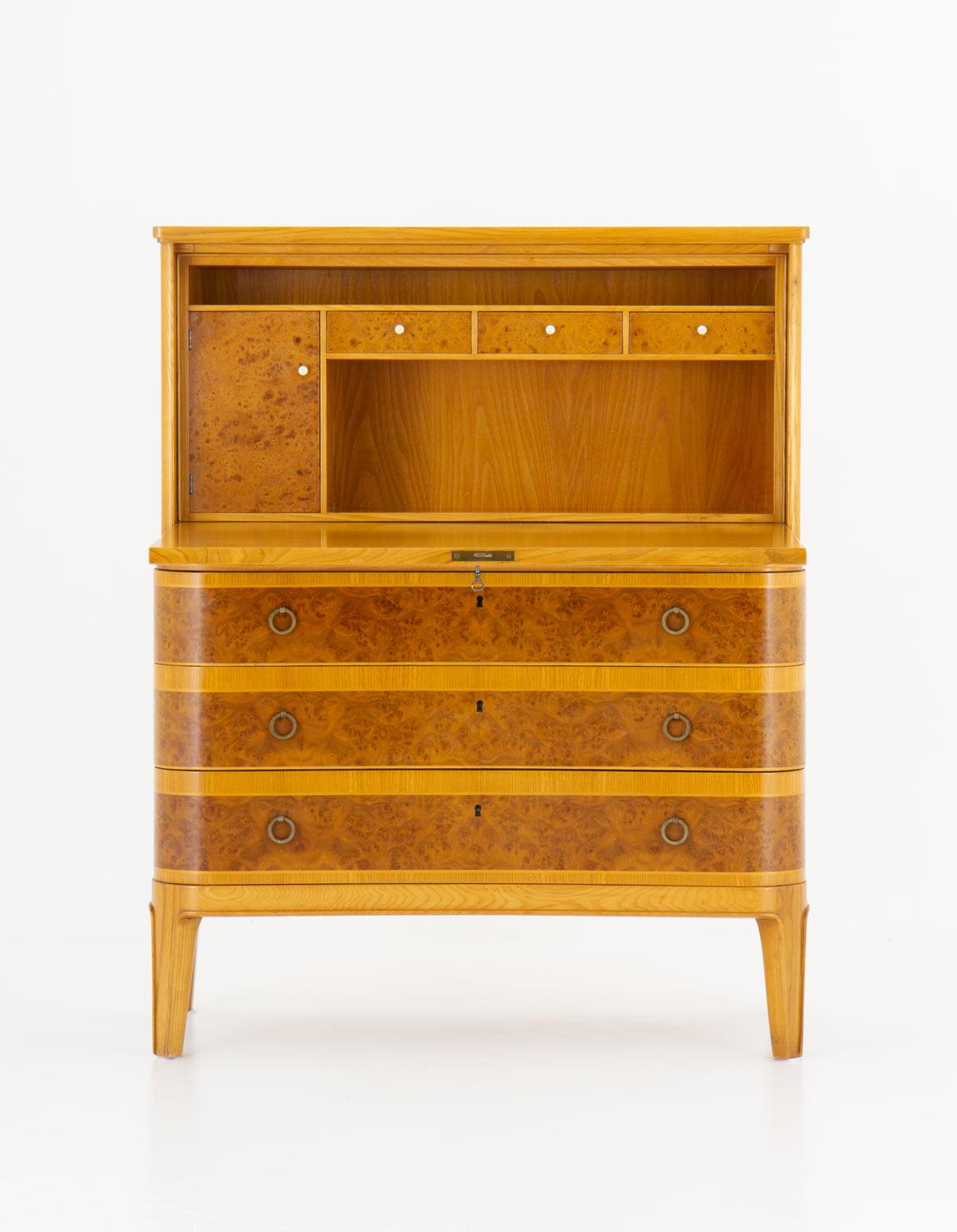 Beautiful bureau by Åby Möbelfabrik, Sweden, circa 1940.
This bureau is made of elm and elm root veneer. It consist of three drawers and one folding vertical door, hiding three small drawers and a locker. 
The construction quality of this piece is