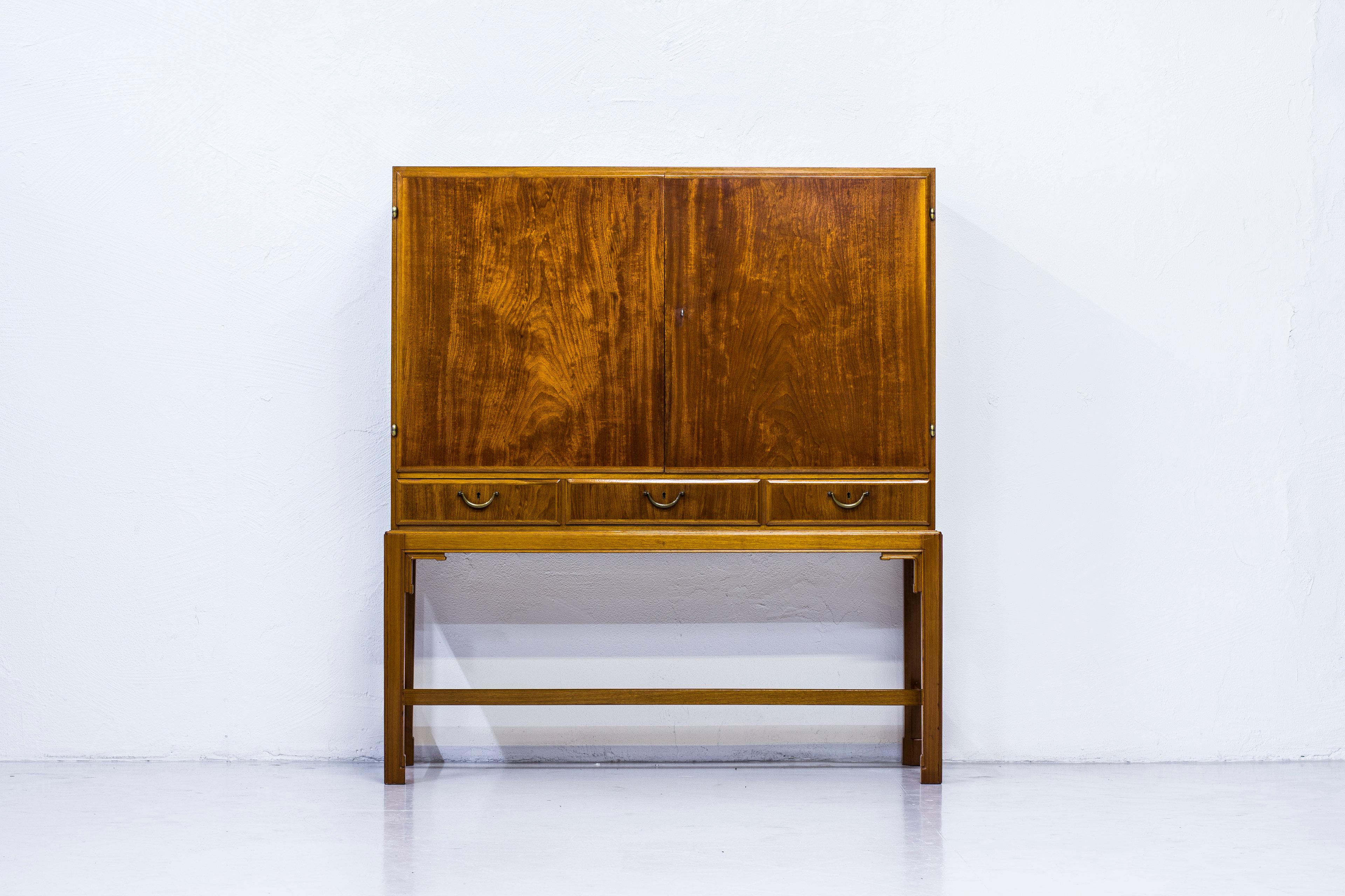 Cabinet designed by Architect John Kärnhagen. Produced in Stockholm Sweden by his own workshop in 1948.  Outside made from elm and mahogany wood. The inside made from beech wood and walnut. Brass handles and hinges. One original key.  Very good