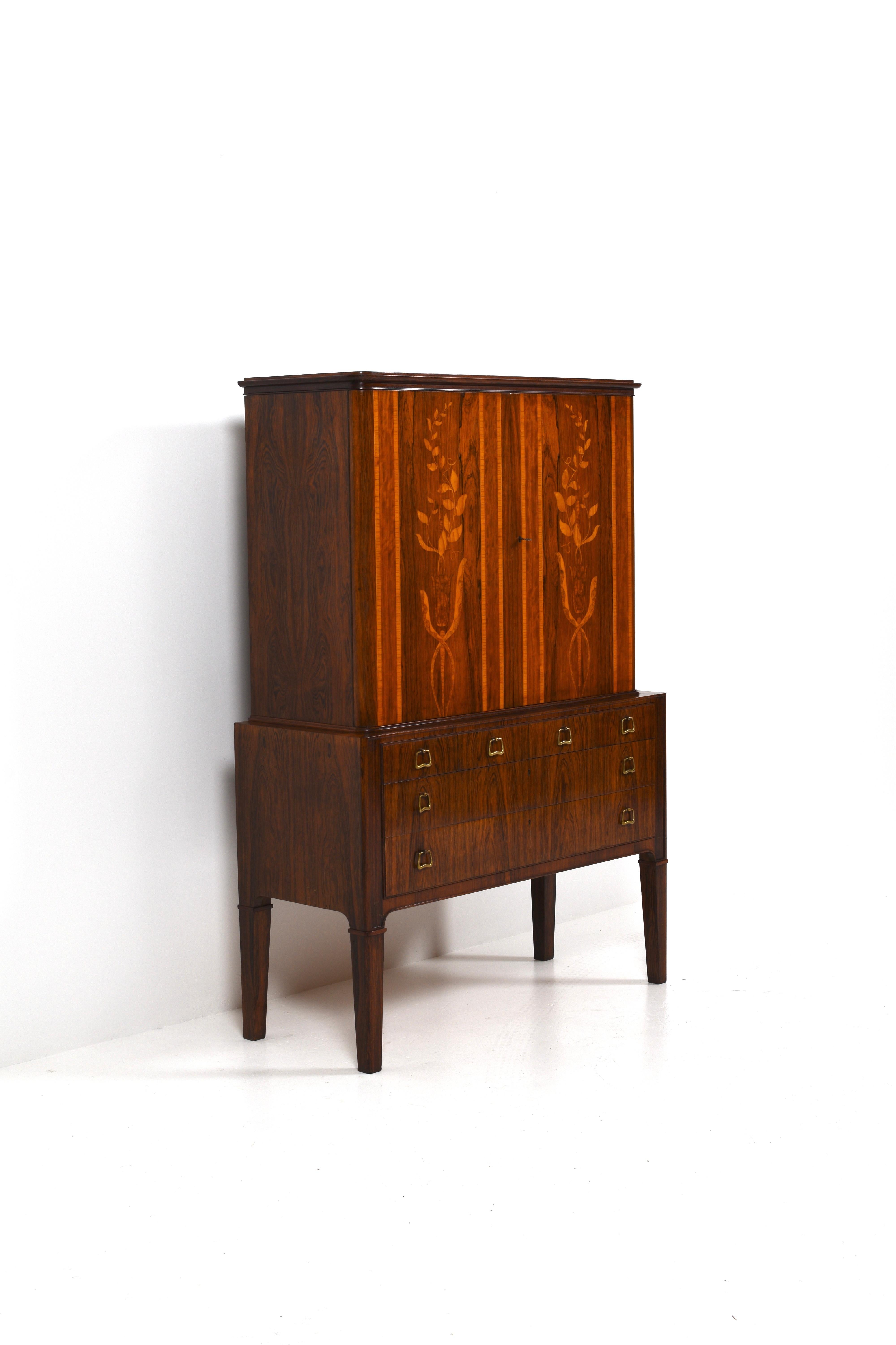 This cabinet is crafted from fine rosewood, featuring a beautifully rich and warm patina that enhances its natural elegance. The exterior is adorned with intricate intarsia, showcasing delicate floral patterns that add a touch of artistry and