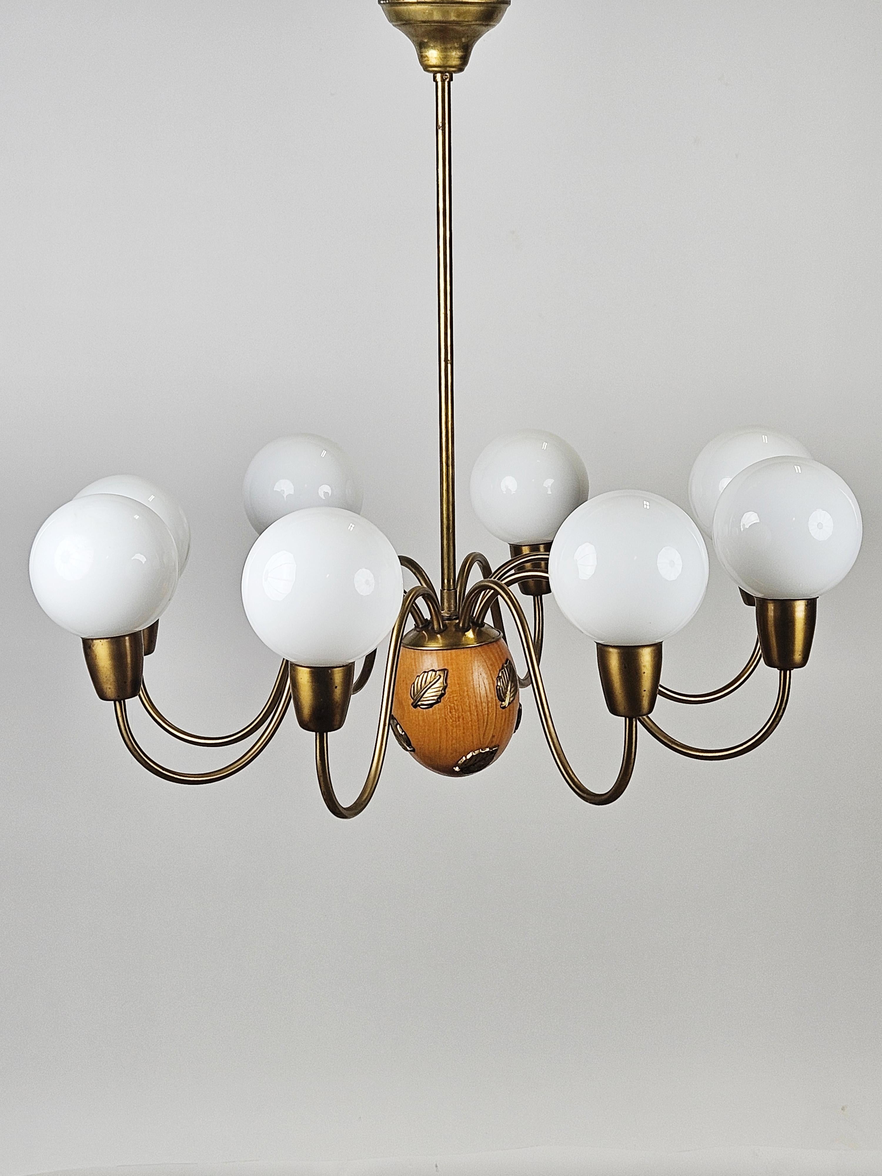 Eight armed chandelier designed by Hans Bergström and produced by his own firm Ateljé Lyktan in the 1940s. 

Elegant design with wood and brass details. Sculptured arms with glass globes. 