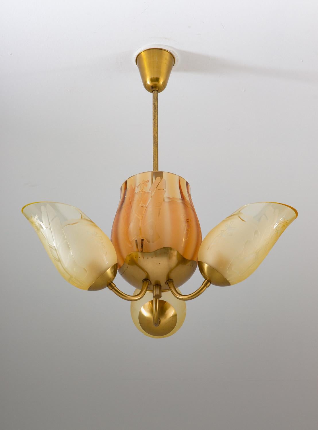 Rare chandelier by Swedish manufacturer Glössner, 1940s.
This impressive lamp features five light sources hidden by glass shades, one large in the middle with two light sources, surrounded by three smaller ones. The large shade is held by a