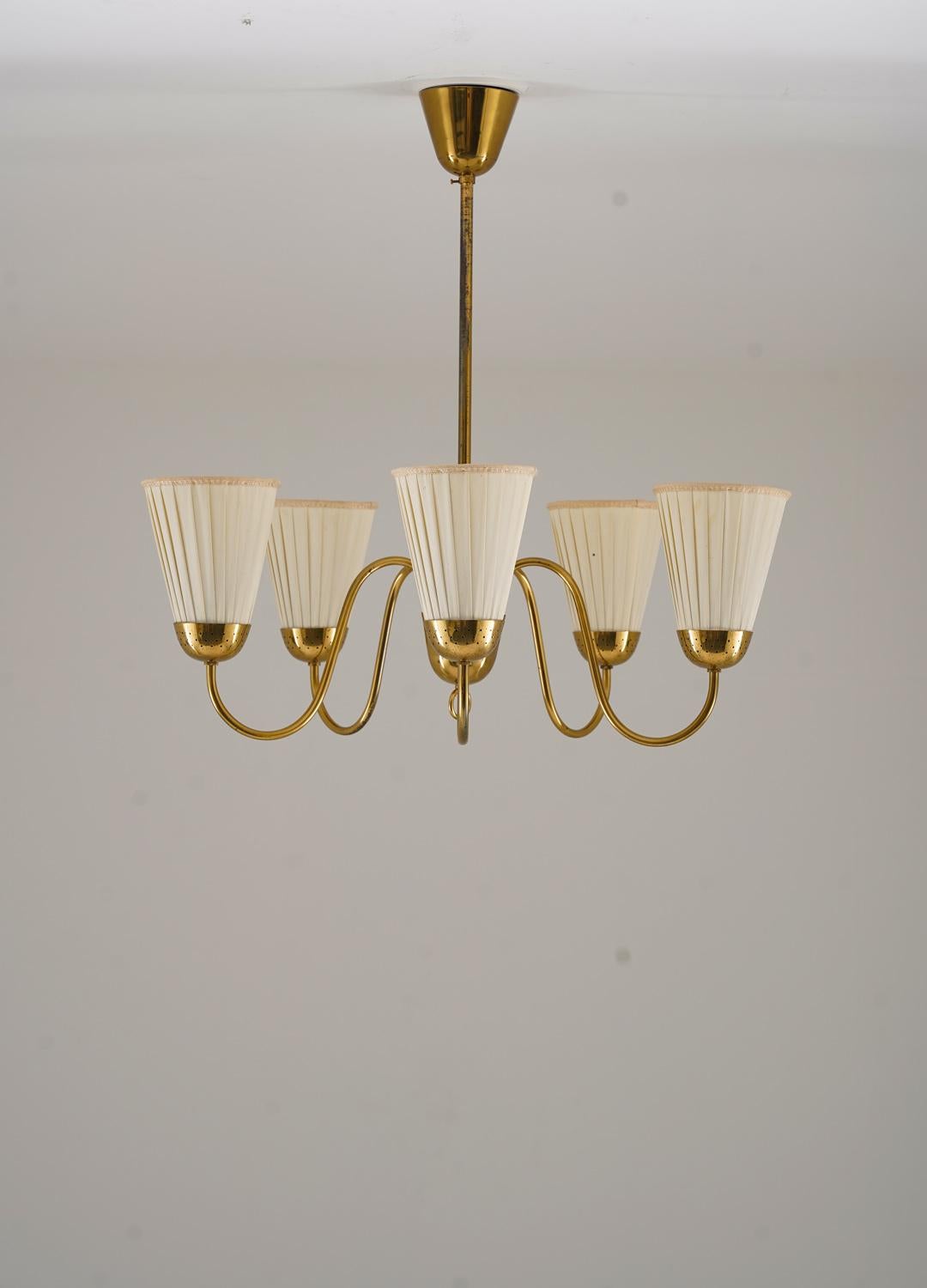 Lampadario moderno svedese molto elegante prodotto da Bergboms, anni '40.
La lampada offre 5 sorgenti luminose, sostenute da supporti in ottone perforato e circondate da paralumi originali in tessuto.

Condit: Buone condizioni originali con alcune