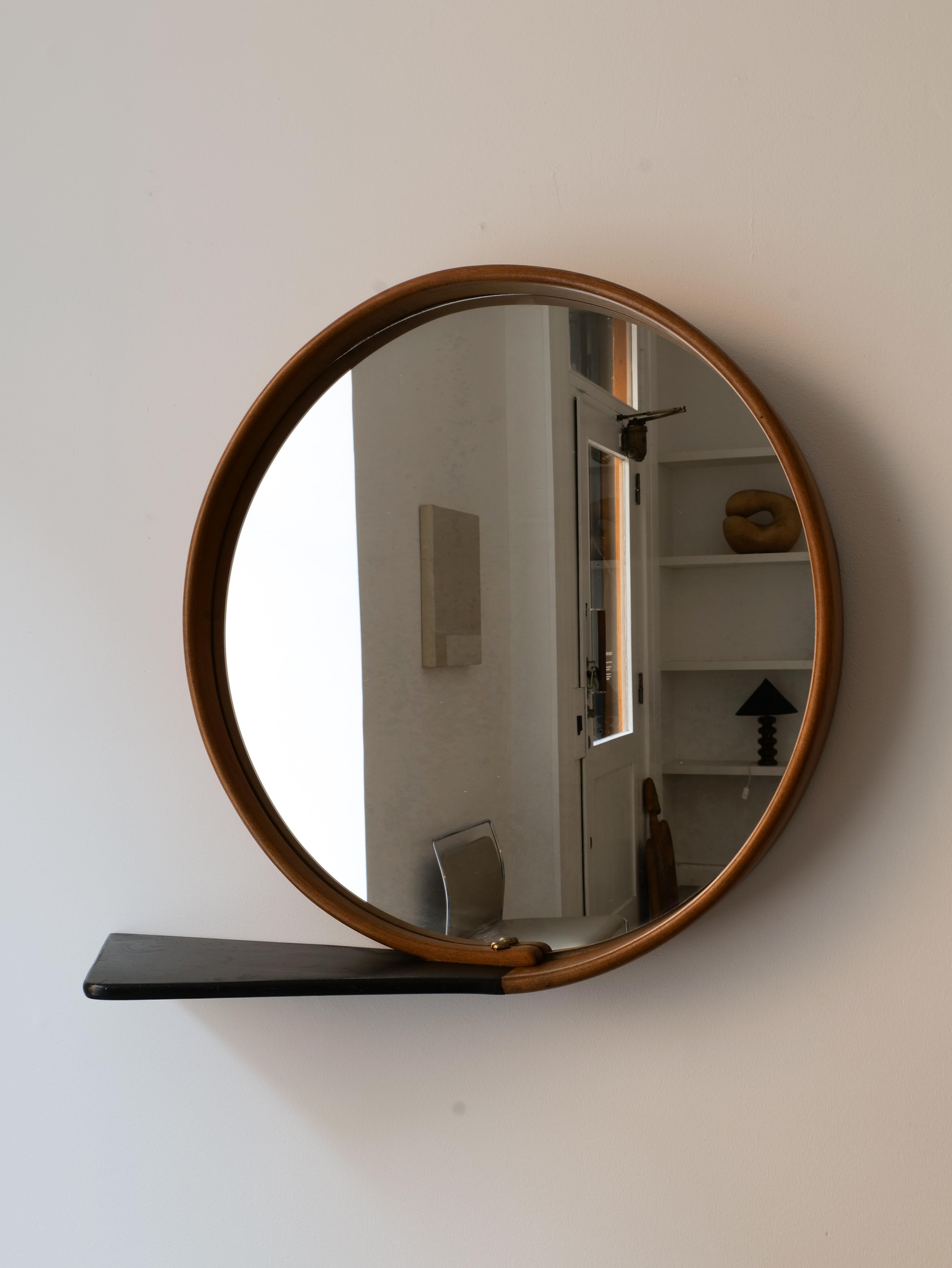 Ein wunderschön gearbeiteter, kreisförmiger Spiegel der schwedischen Moderne, der in einer Schlaufe aus Holz um den gesamten Spiegel herum geformt ist. Messingstifte halten die Schlaufe mit einem verlängerten Stück, das als kleine Ablagefläche