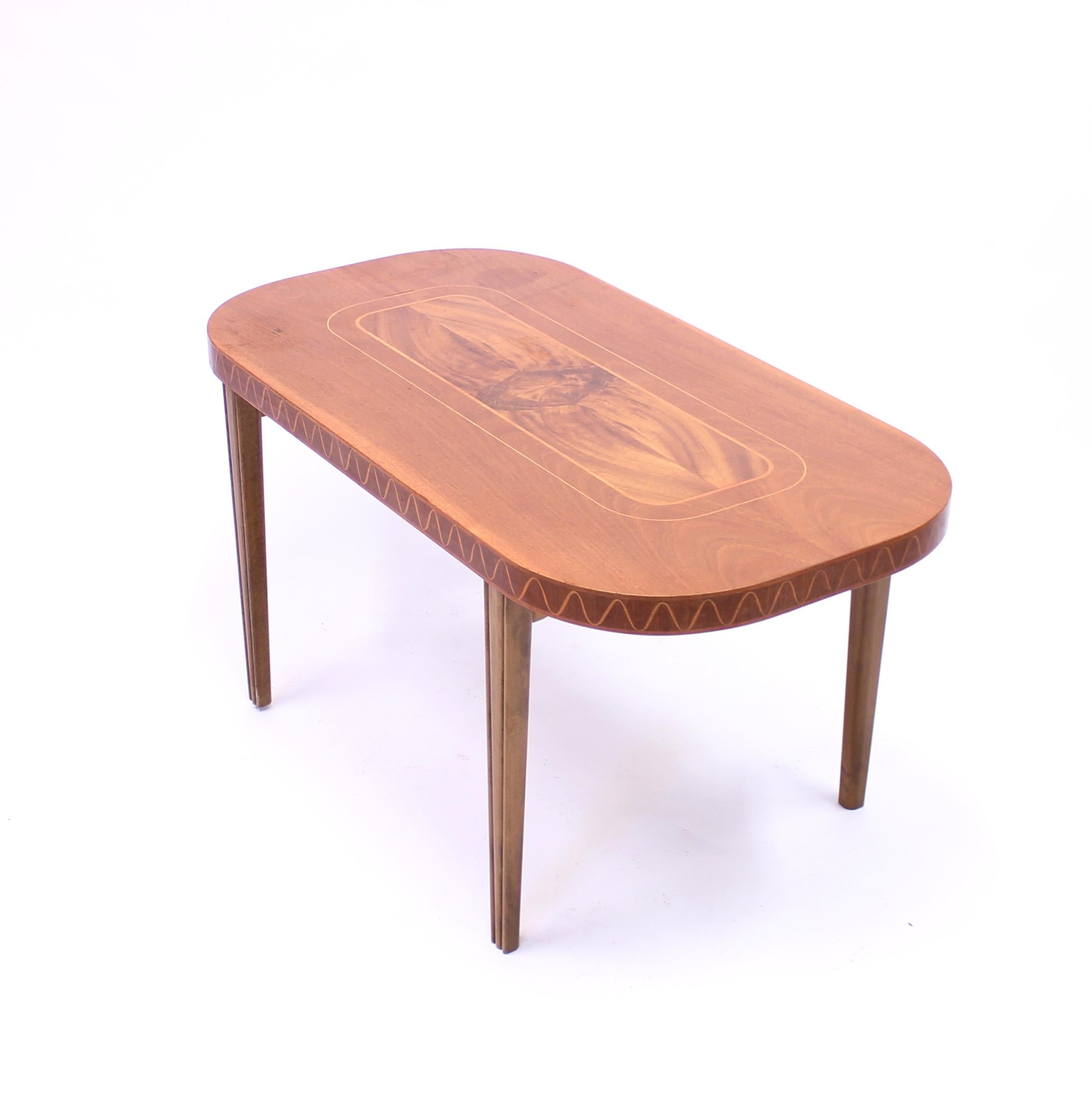 Coffee table from the 1940s in the Swedish Modern style with inlay of multiple wood types, including mahogany, birch and maple. Inlay of wave motif on the side of the table top. Good vintage condition with normal ware consistent with age and use