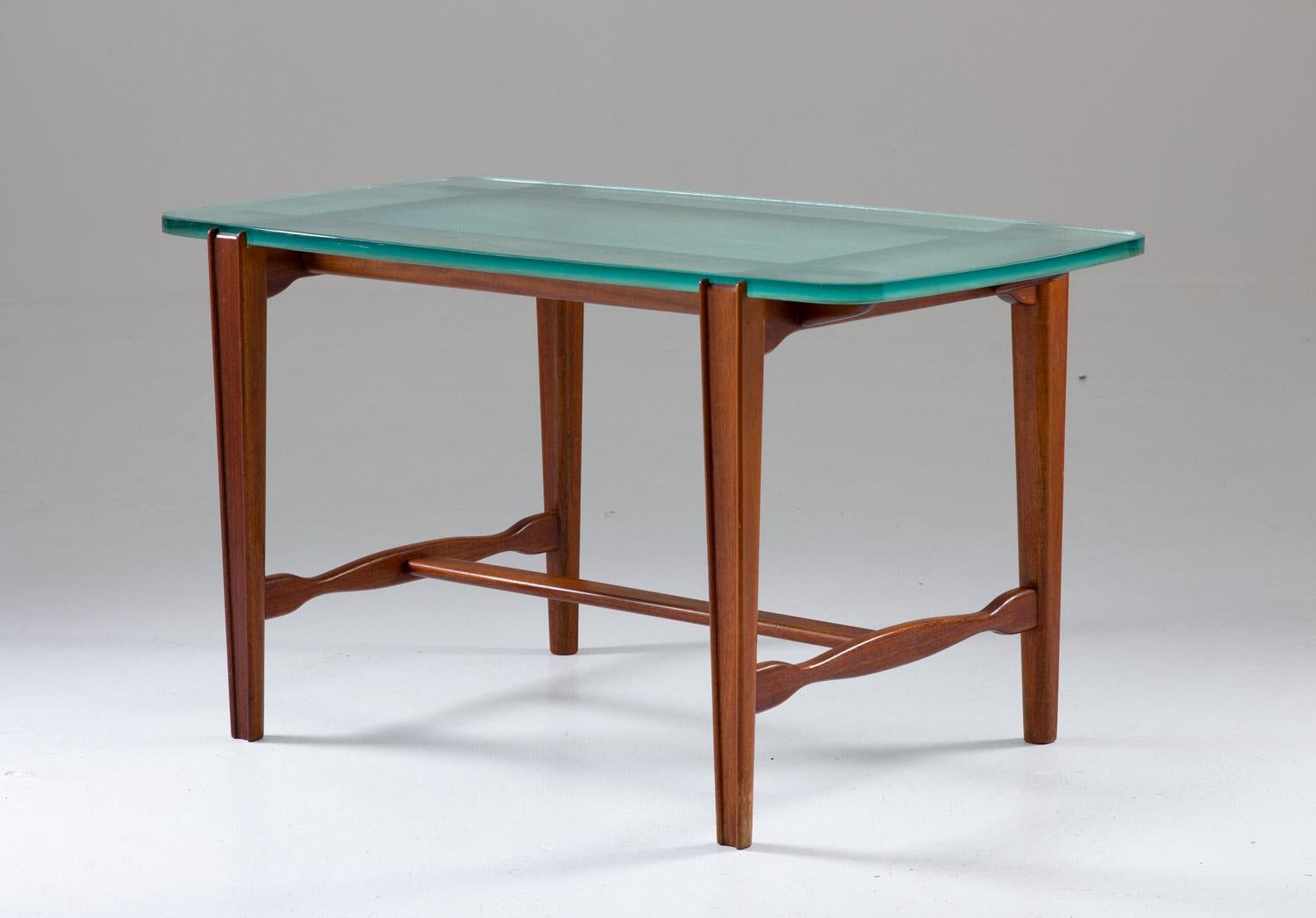 Beautiful coffee or side table on mahogany and glass by unknown Swedish manufacturer, circa 1940.
The table consists of a thick raw-glass table top, supported by a mahogany frame/legs. The thickness of the glass top gives an exclusive impression