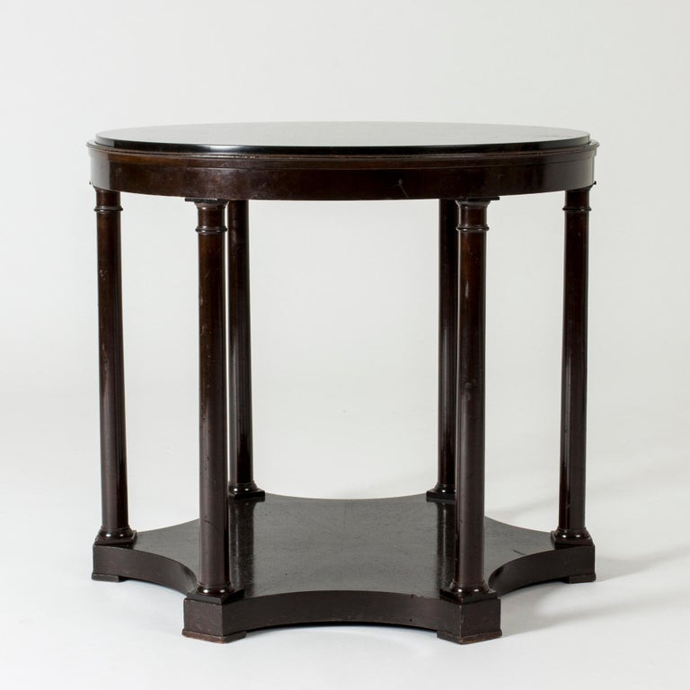 Elegant console table by Axel Einar Hjorth, with a round black marble table top. Multiple legs with decorative sculpted details.