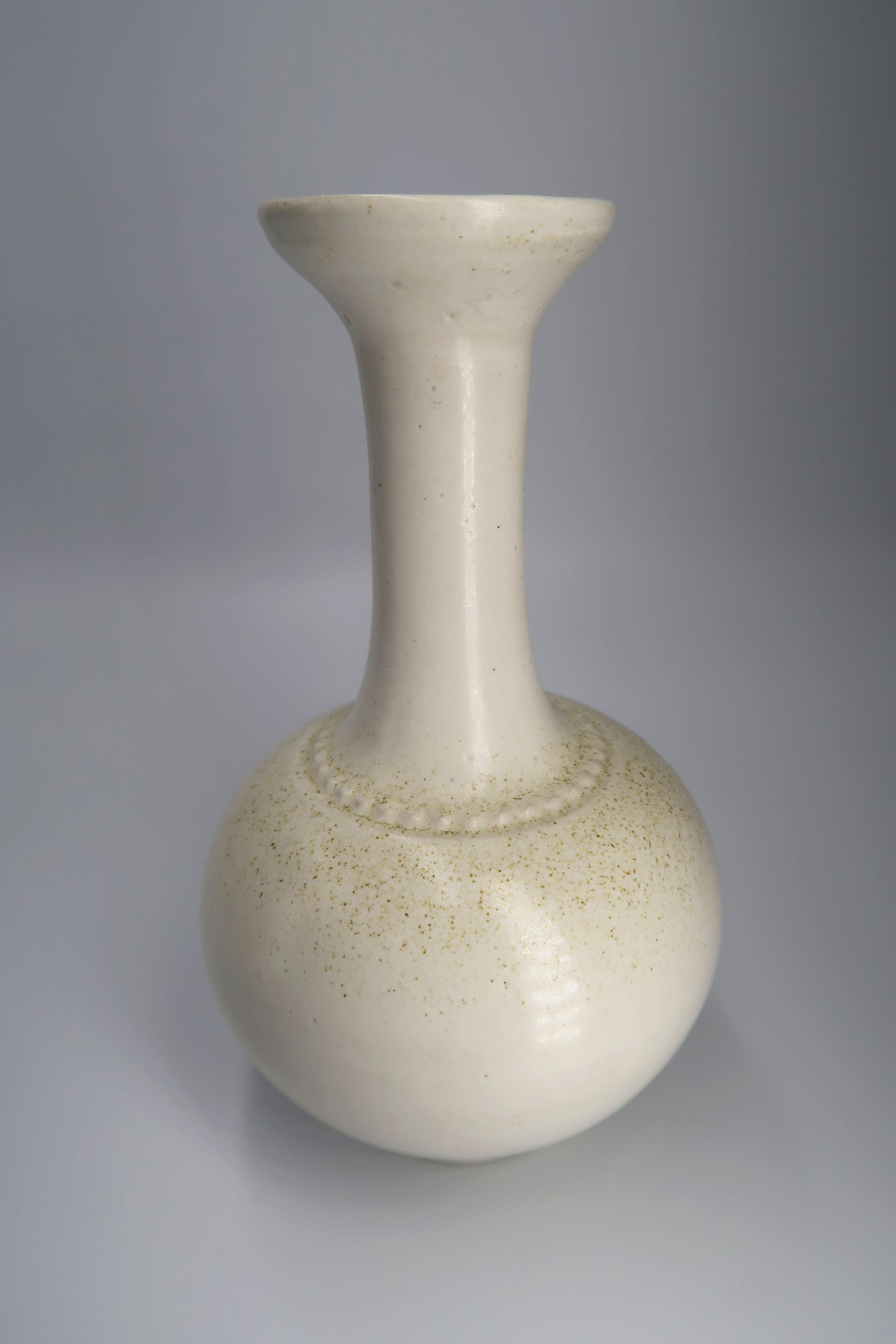 Elegantes Beispiel für klassische skandinavische Handwerkskunst der Jahrhundertmitte. Handgefertigte Vase aus Steingut mit cremeweißer Glasur. Fein gepunktetes Muster um den Halsansatz und winzige braune Akzente in der Glasur, die das Muster