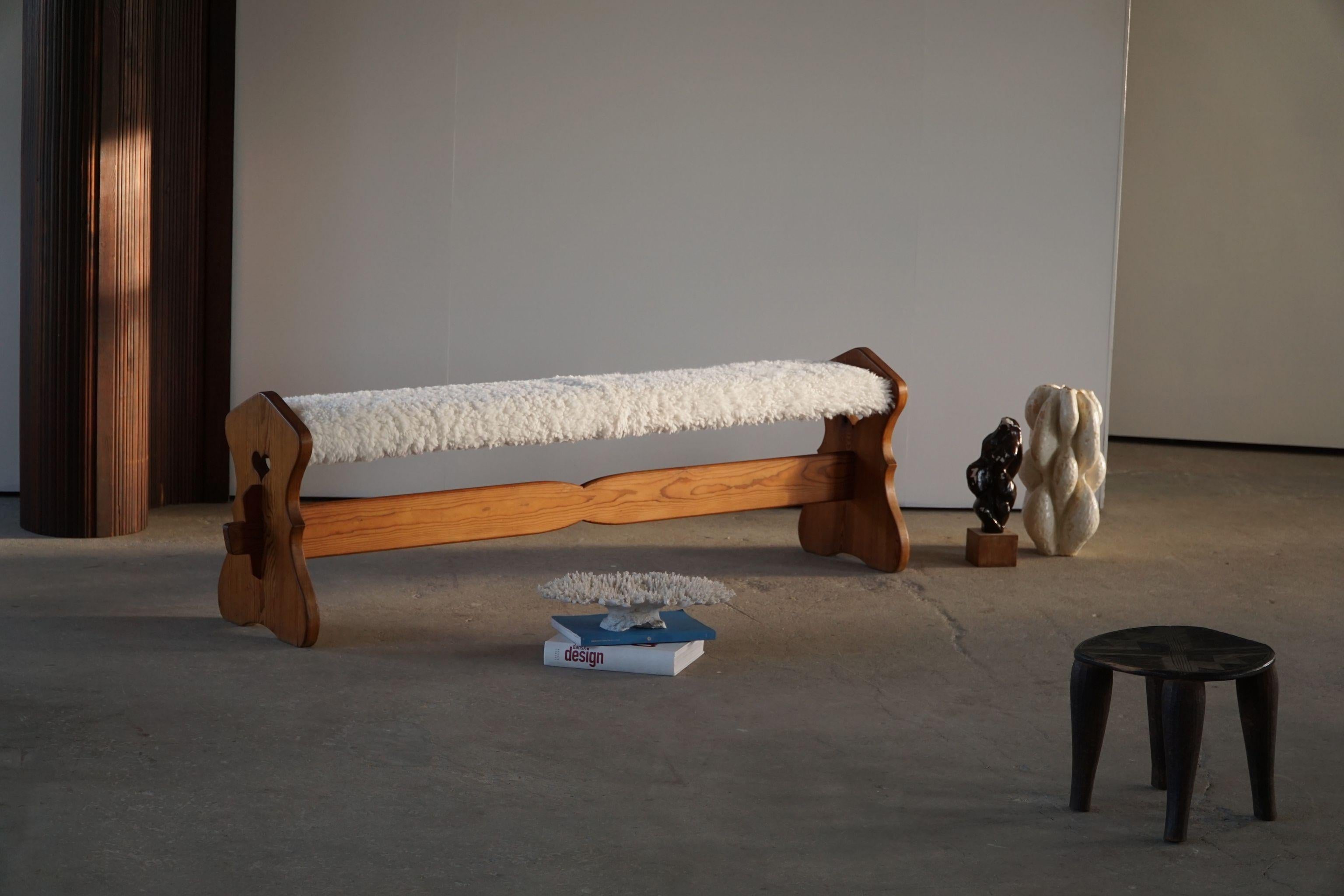 A unique sculptural folk art bench in solid pine. Reupholstered in good quality shearling lambskin. Handcrafted by an unknown cabinetmaker in Sweden, ca 1940s. This beautiful bench can be used in a hallway, around the dining table or a sculptural