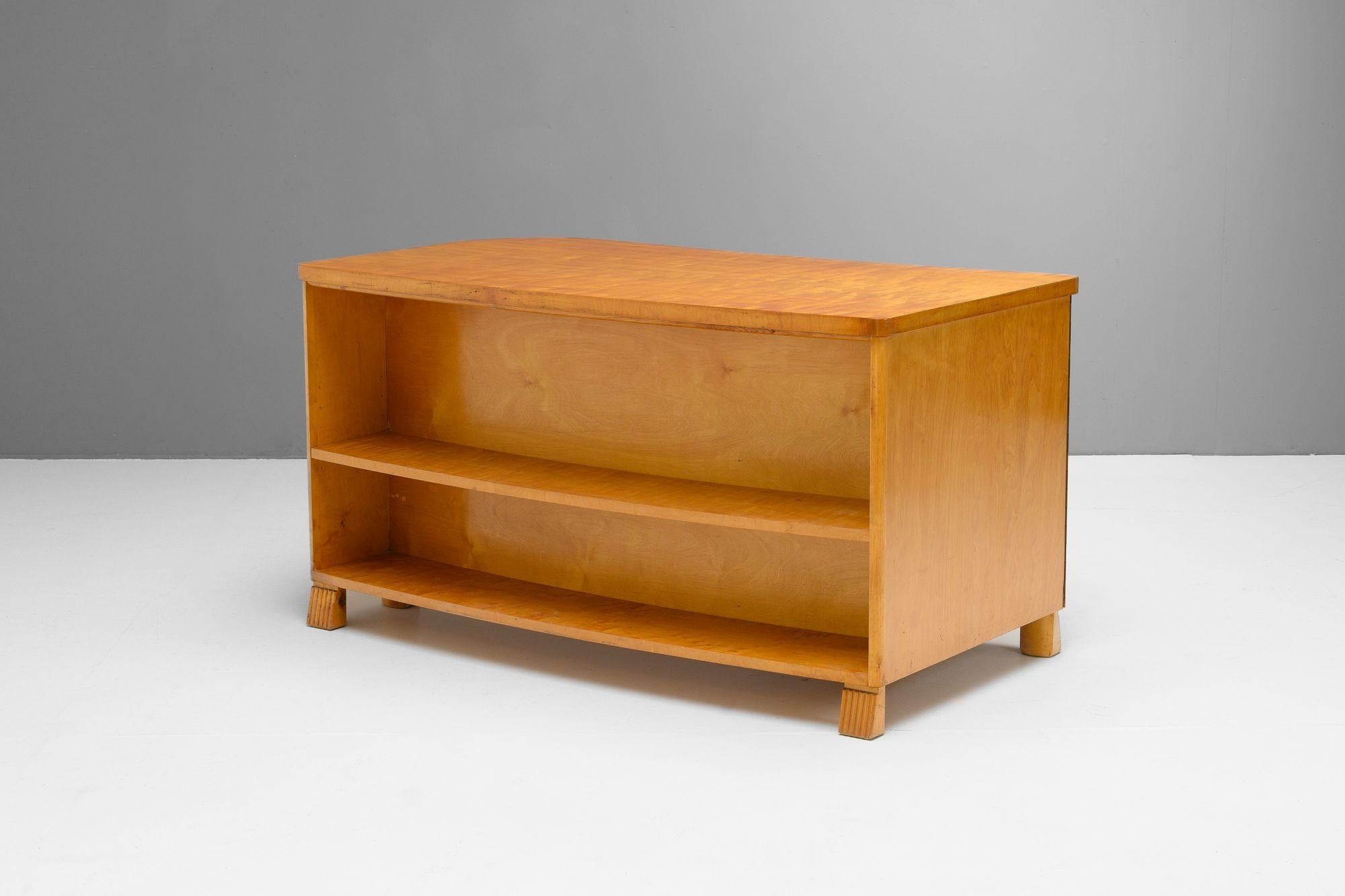 Scrivania svedese in betulla satinata. Design moderno svedese messo in risalto dalla forma organica, un armadio con cassetti, un ripiano galleggiante per la carta e una libreria frontale. Rifinito. Svezia, circa 1940.

H. H. 72cm x L. 135cm x P. 72cm