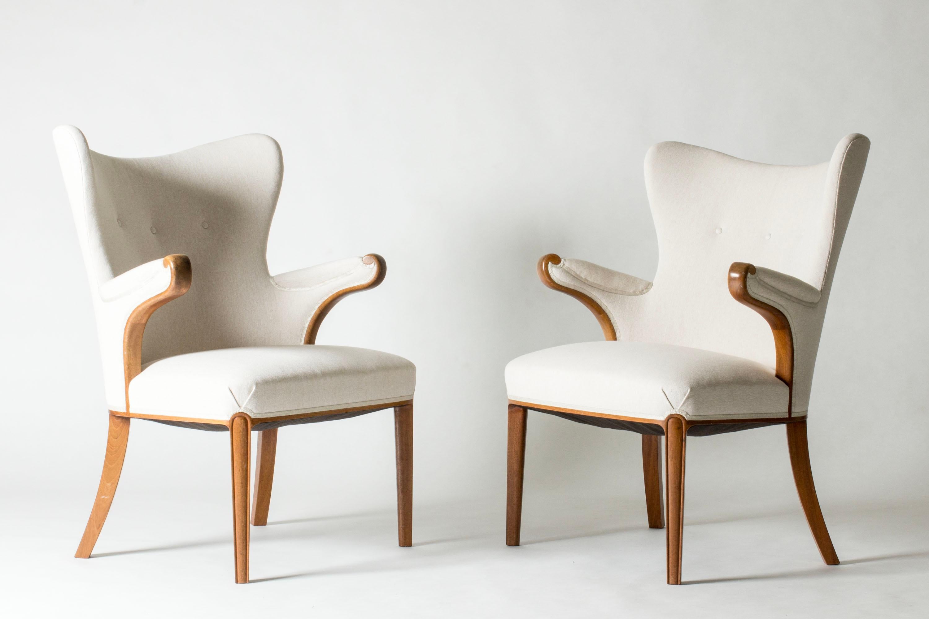 Pair of beautiful Swedish Modern easy chairs, made from wood with flowing lines and elegant details. Upholstered with linen fabric.