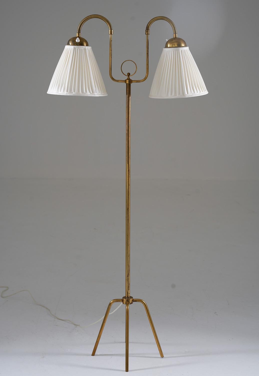 Swedish Modern floor lamp in brass, manufactured during the 1940s.
This elegant floor lamp has two light sources on adjustable arms.

Condition: Good original condition with patina (dark spots on the brass). The lamp comes with new hand-pleated