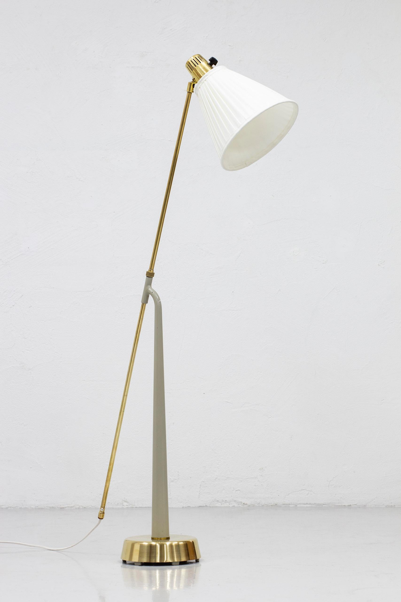 Floor lamp model 541 designed by Hans Bergström. Produced by Ateljé Lyktan ca 1940-50s.The lamp consists of a brass base with the main lamp stem in a light grey lacquer. The stem holds and adjustable arm on an angle also in brass. Lamp fitting has