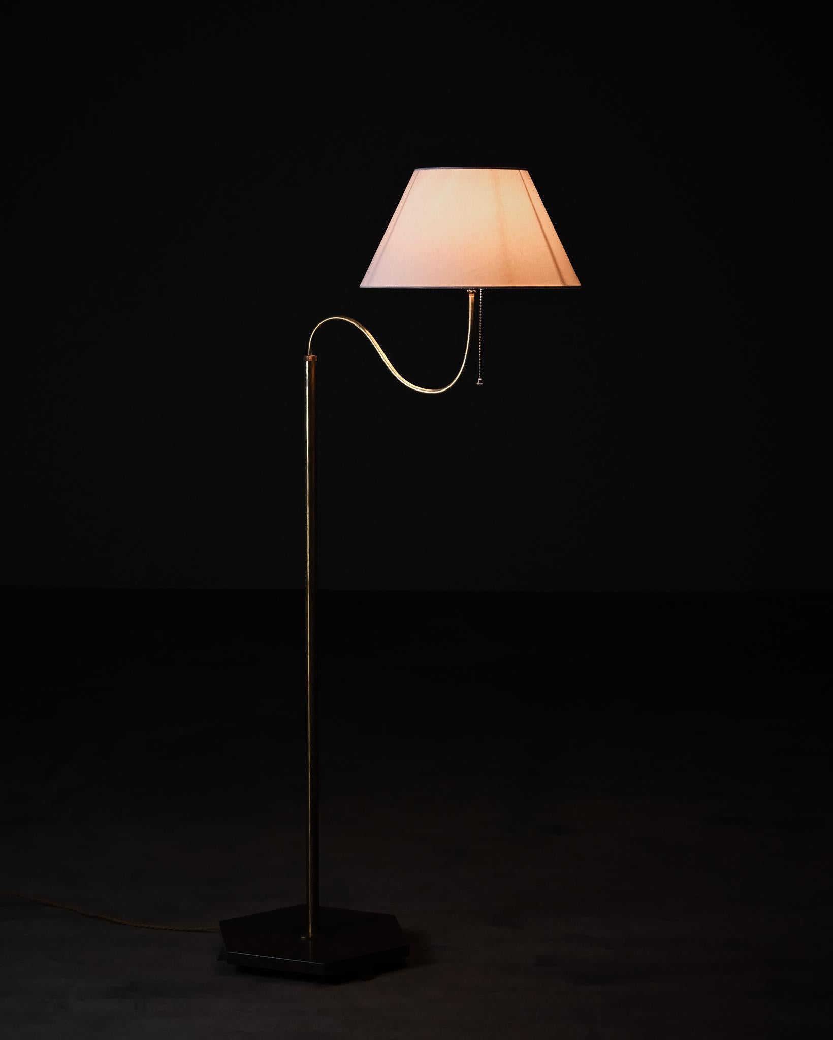 Lampada da terra moderna svedese della metà del XX secolo, designer e produttore sconosciuti.

Base in pietra calcarea rossa con accessori in ottone massiccio. Un braccio ampio e curvo sostiene il paralume e conferisce al pezzo la sua silhouette
