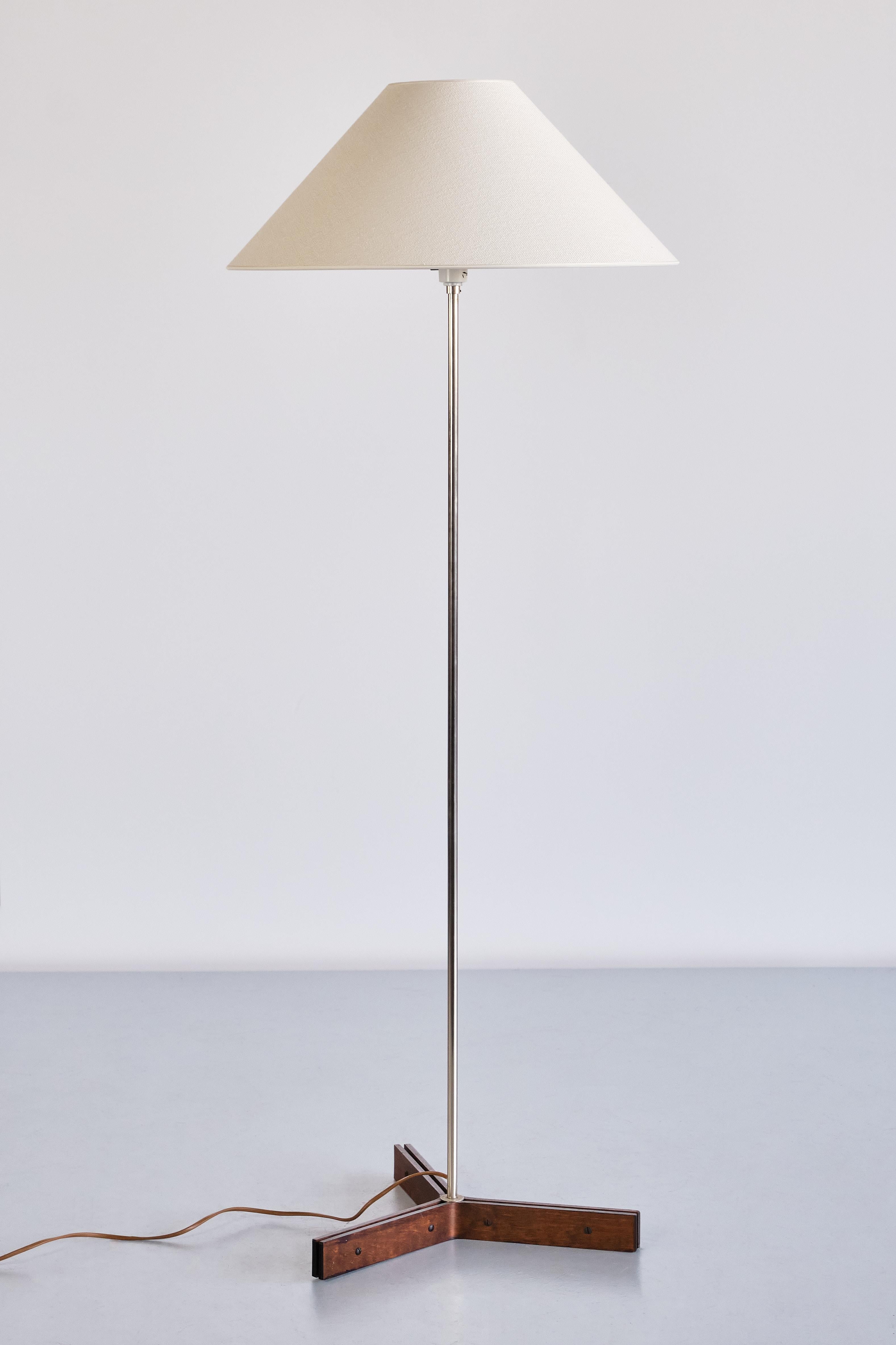 This elegant, tall floor lamp was produced by the Swedish manufacturer NAF Nybro Armatur Fabriken in the 1970s. The design is marked by the central thin stem in silver steel, resting on a triangular base. The base is made of curved strips of wengé