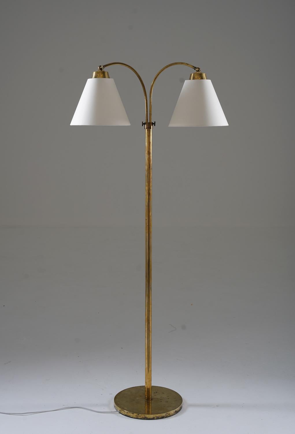 Lovely Swedish Modern floor lamp manufactured in Sweden, 1940s. 
The lamp consists of a base and rod in brass, supporting two swivel arms that hold the shade. The swivel arms are adjustable in height

Condition: Good vintage condition with