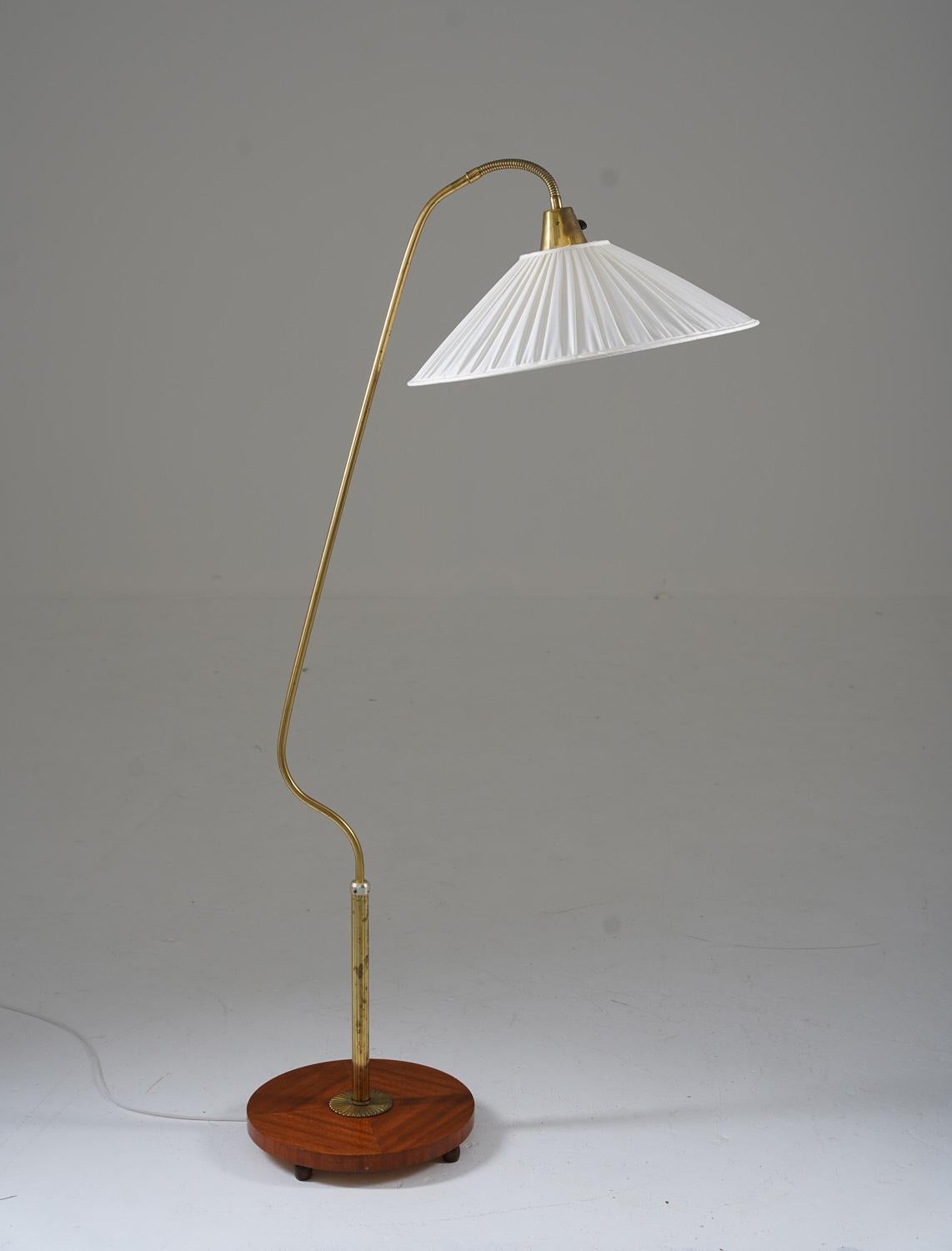 Dies ist eine schöne schwedische moderne Stehlampe, die in den 1940er Jahren in Schweden hergestellt wurde. Die Lampe verfügt über einen Holzsockel und eine Messingstange, die einen verstellbaren Fedderarm trägt, der den Schirm hält.