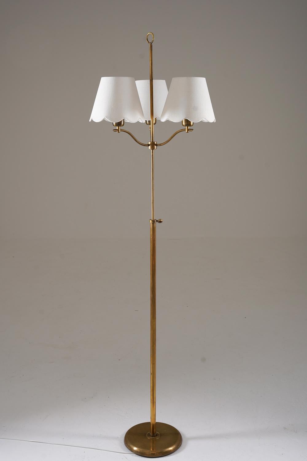 This is a lovely Swedish Modern floor lamp that was manufactured in Sweden during the 1940s. The lamp features a brass base and rod, supporting a slimmer rod that is adjustable in height (60