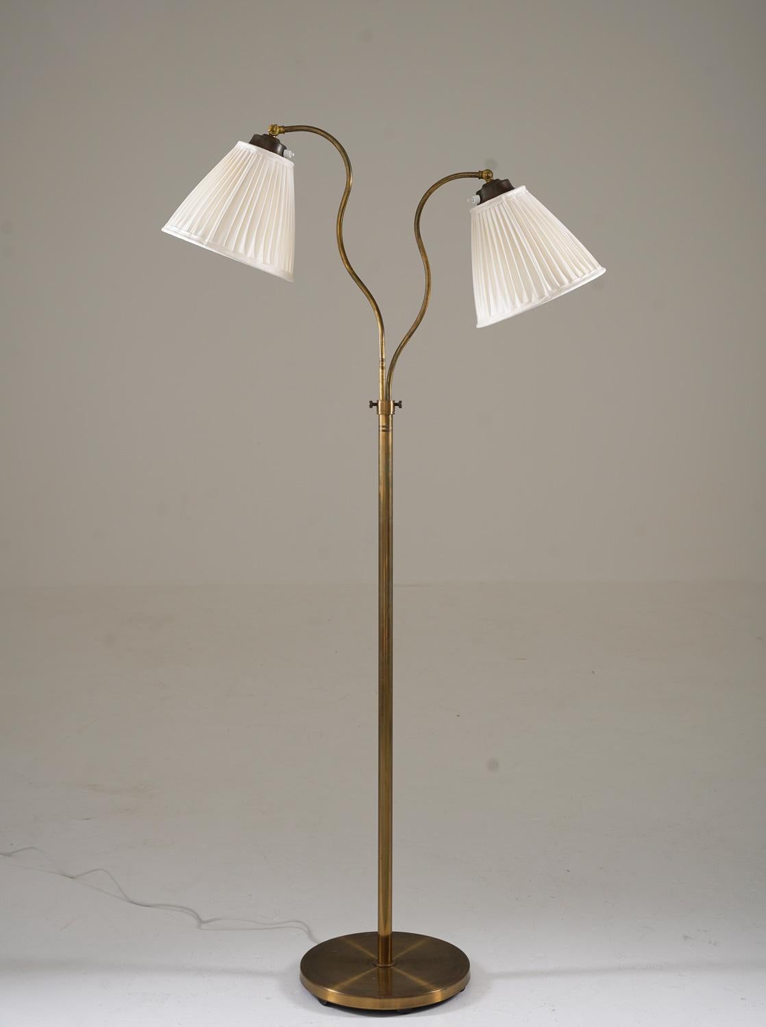 This is a lovely Swedish Modern floor lamp that was manufactured in Sweden during the 1940s by Corona.
The lamp features a brass covered iron base and a brass rod, which supports two swivel arms that hold the shades. The swivel arms are adjustable