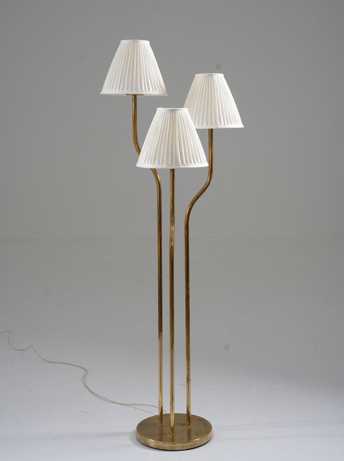 Rare floor lamp manufactured in Sweden, 1940s. 
This floor lamp consists of a beautiful brass base, holding three brass rods, one for each light source. The bulbs are hidden by new custom-made hand-pleated chintz fabric shades

Condition: Very