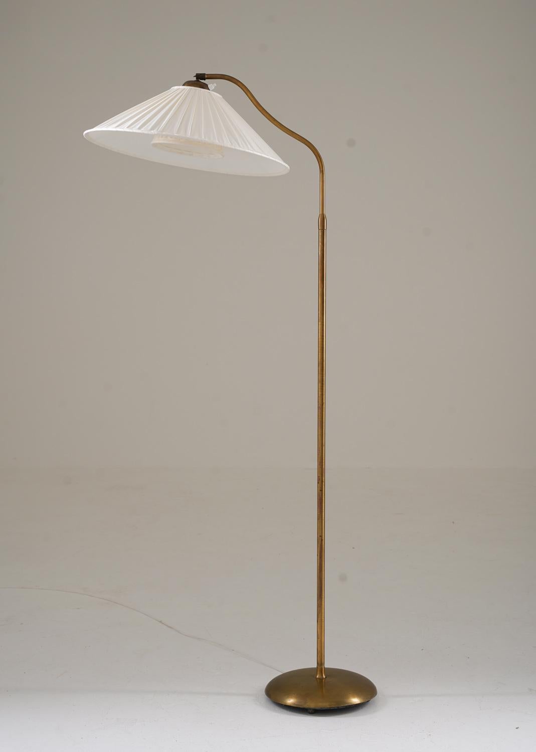 This is a lovely Swedish Modern floor lamp that was manufactured in Sweden during the 1940s.
The lamp features a brass-coated iron base and a brass rod, which supports a swivel arm that holds the shade. The swivel arm is adjustable in height,