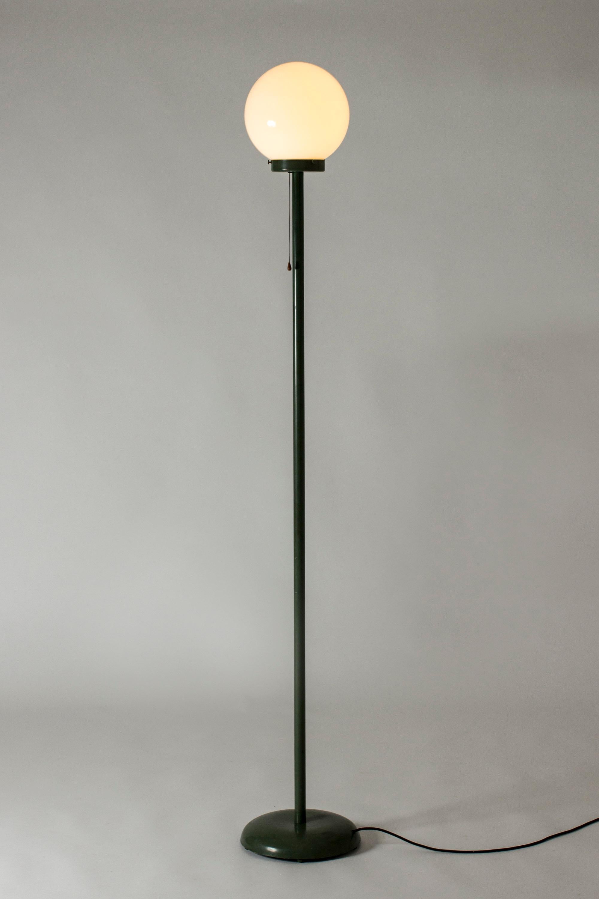 Cool functionalist floor lamp, in a very tall size. Made from lacquered green metal, round glass shade. Very nice proportions. Looks great in a room with a high ceiling.
