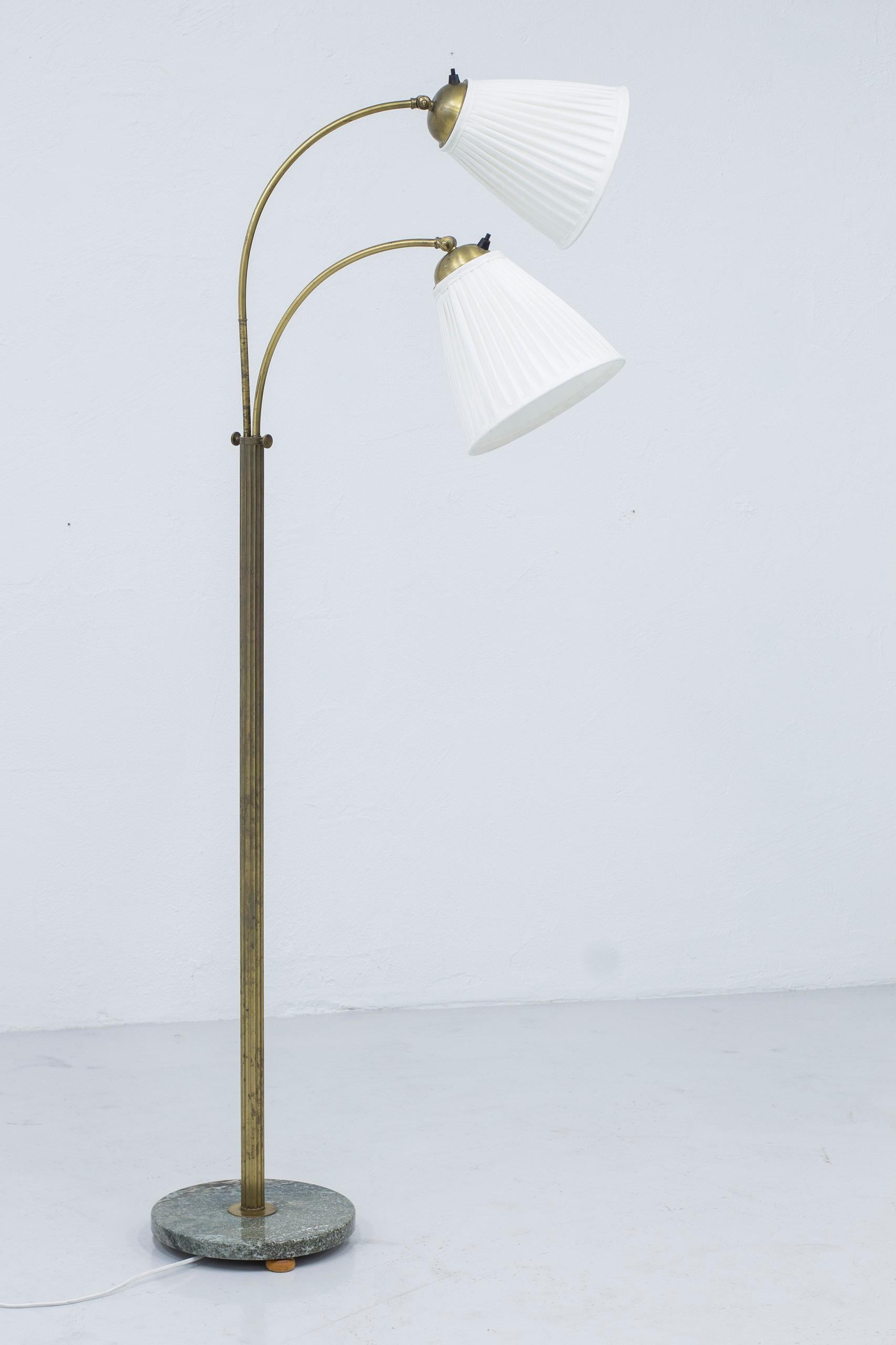 Swedish Modern floor lamp by unknown maker and designer. Made in Sweden ca 1940s. Fluted brass stem with two adjustable arms with custom brass hardware. Base made from Swedish 