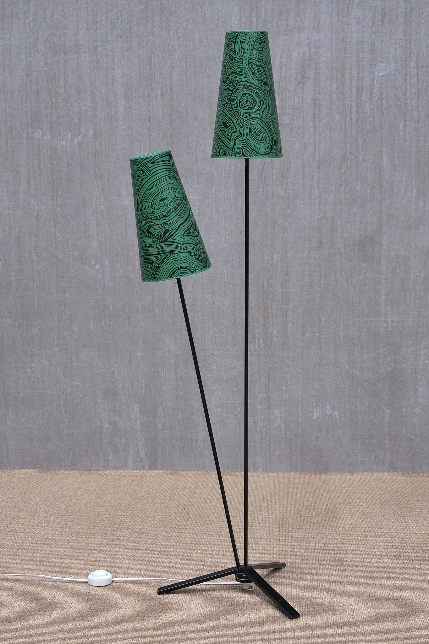 This striking floor lamp was designed in Sweden in the 1950s.

The design features a three-legged base in black lacquered metal. Mounted on top of the base are two tubular arms, also in black lacquered steel. The differing heights and angled
