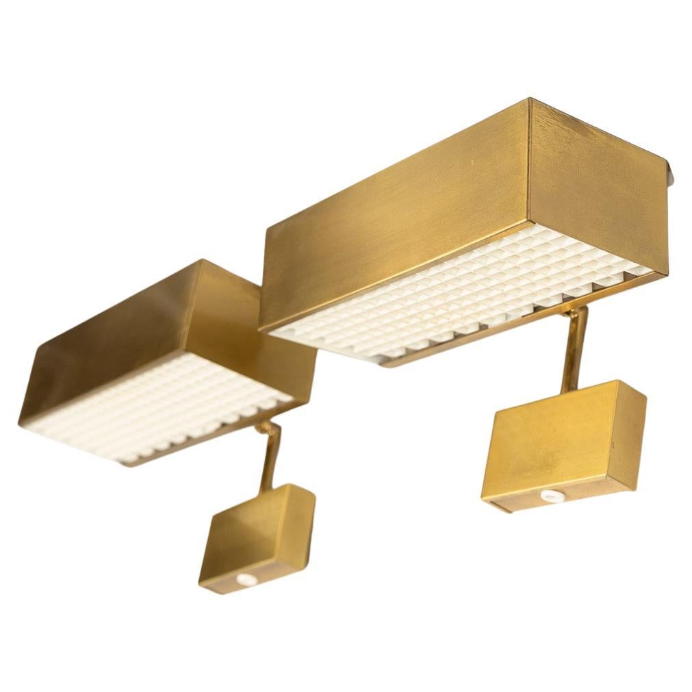 Un set minimalista di lampade da parete regolabili realizzate in ottone massiccio con finitura opaca. Ha un paralume in acrilico che copre la lampadina. Questo pezzo è stato prodotto in Svezia negli anni '70.
La sezione inferiore mostra un'etichetta