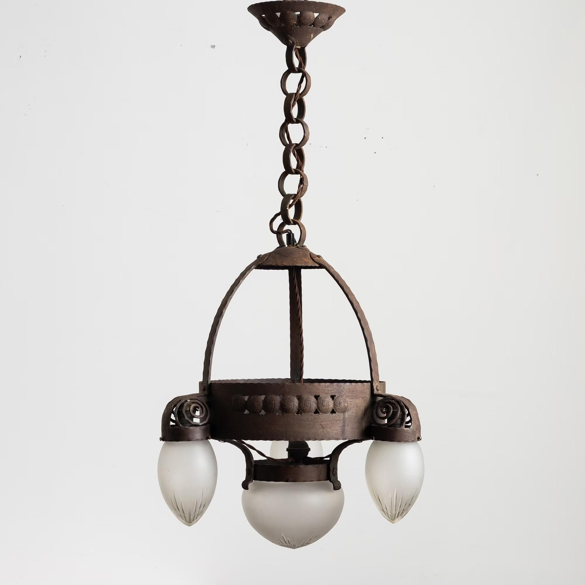 A very rare and early Swedish modern jugend / art nouveau ceiling chandelier pendant lamp in patinated iron and four hand blown frosted glass shades with a beautiful decor produced by Arvid Böhlmarks Lampfabrik in Sweden during the 1910s. In good