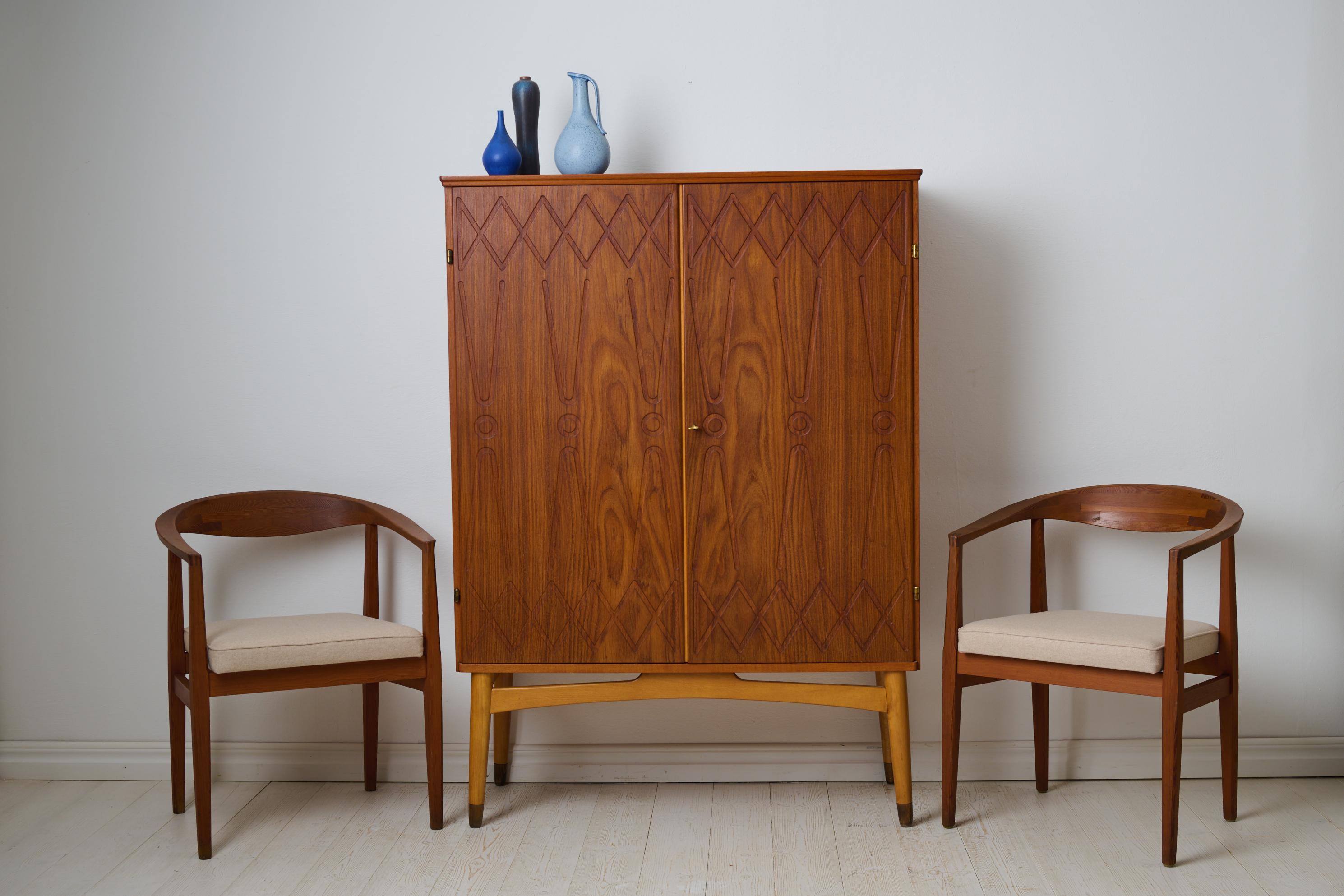 Swedish modern teak cabinet ”Rickard” designed by Kirke Nielsen and made by Abrahamssons Möbelfabrik in Smålands Taberg. The cabinet is from the mid 20th century, during the 1950s and features a pair of doors with embossed decor. The doors open to