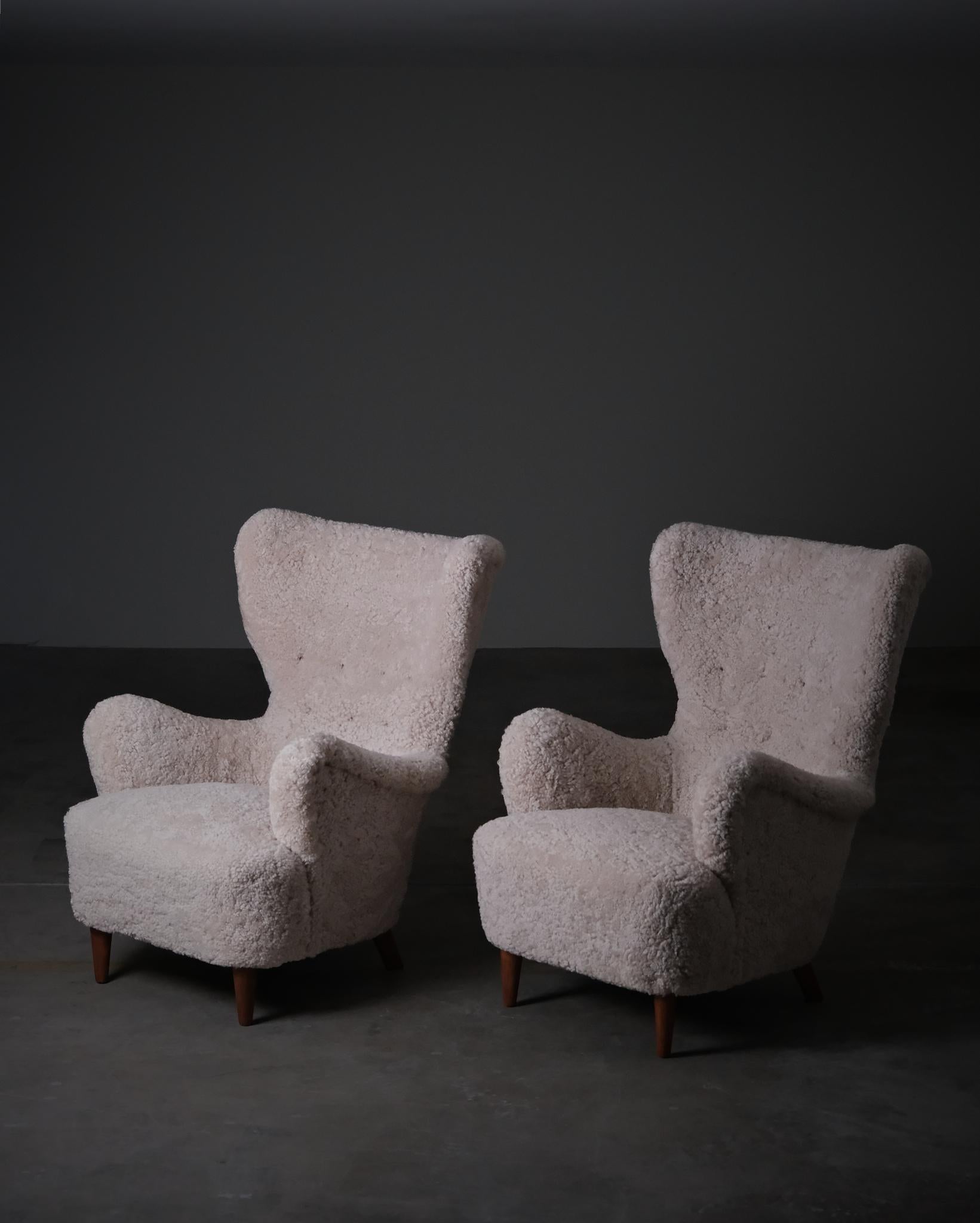 Paire de chaises de salon modernes suédoises d'un designer et d'un fabricant inconnus, produites dans les années 1950. Le modèle présente une forme sculpturale avec un dossier profond et des ailes prononcées, créant une silhouette distinctive et