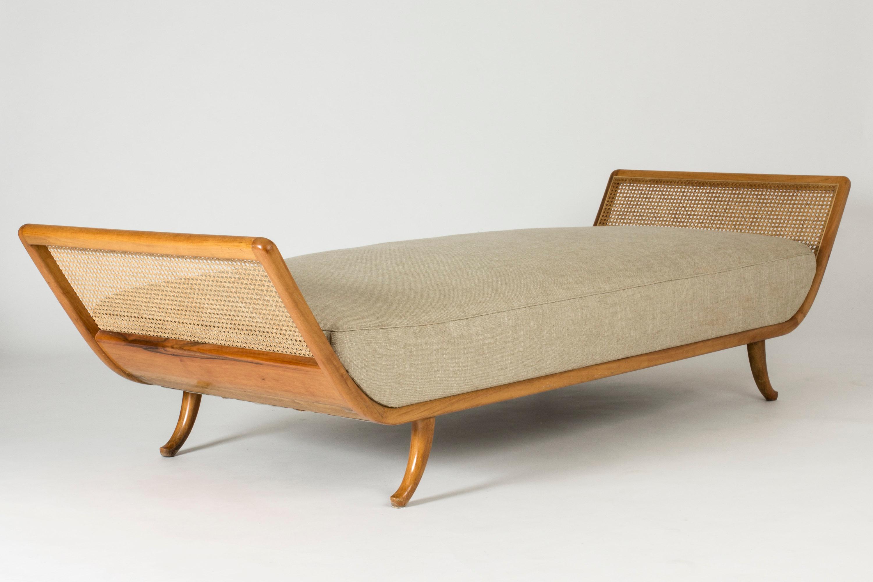 Beautiful Swedish Modern mahogany daybed with rattan on the sides. Lovely open silhouette, clean line of the base of the bed continuing up to the sloping short sides. Seat with springs, upholstered with linen fabric.