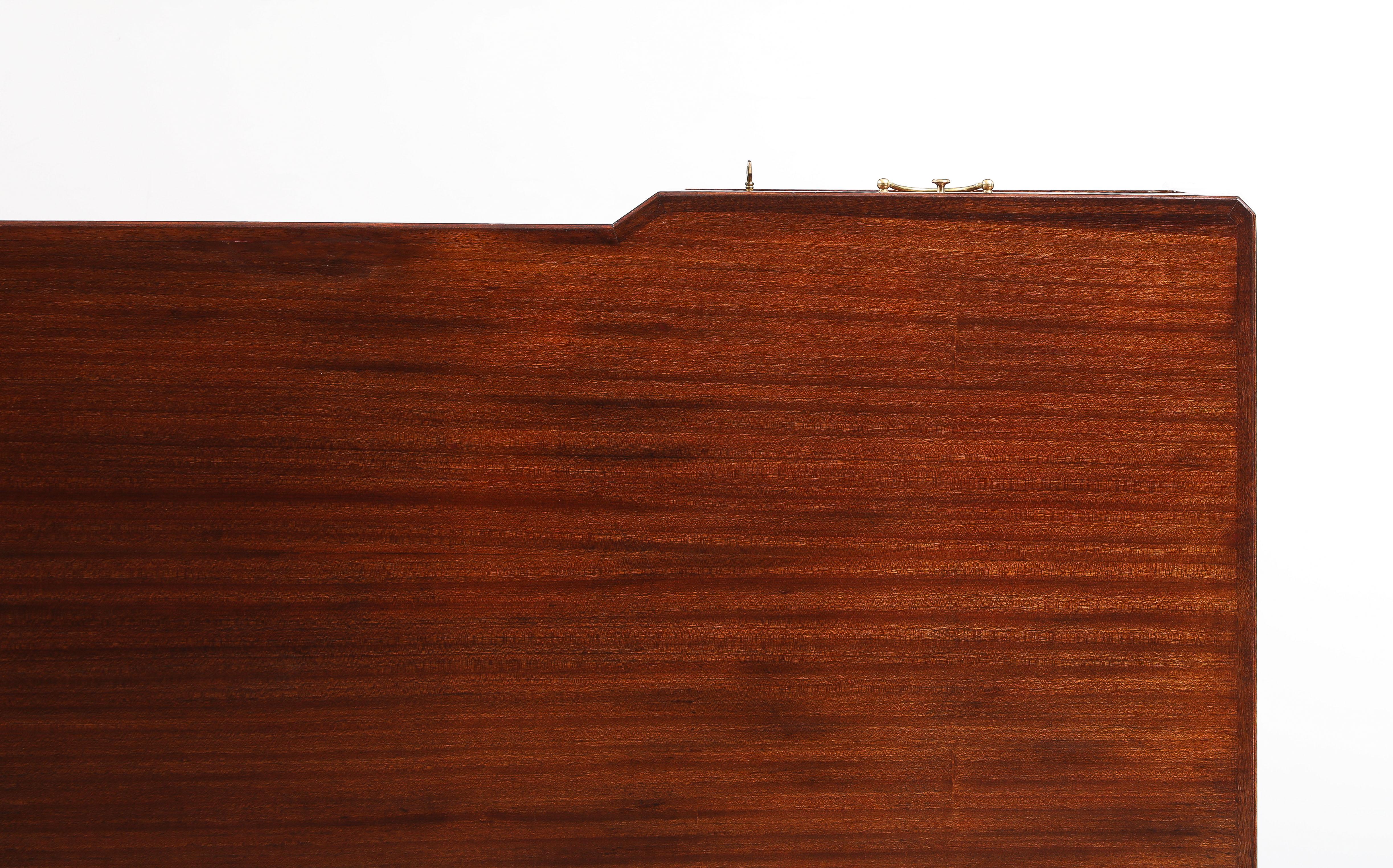 A Swedish Modern freestanding writing desk, in striking mahogany, Circa 1960s, produced and sold by JKM - Järnforsens Kontorsmöbler, Stockholm, Model name : Continental. The rectangular top with long walnut veneers, the sitter edge with a canted