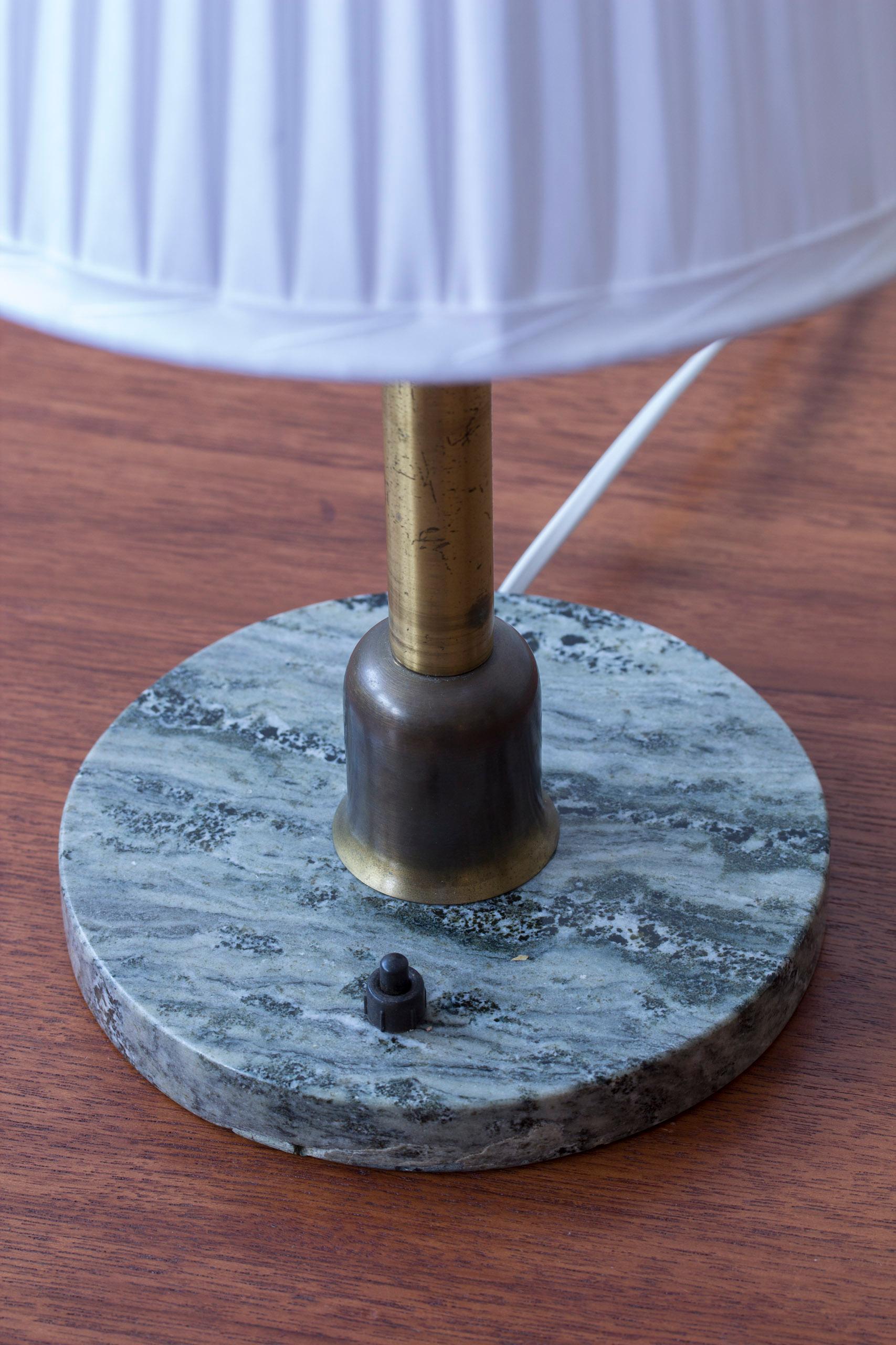 Lampe de table d'un designer et d'un fabricant inconnus. Produit en Suède vers les années 1930-40. Combinaison Loveley de laiton patiné et de marbre suédois Kolmårdsmarmor (marbre de Kolmårds). L'interrupteur sur la base est en état de marche.