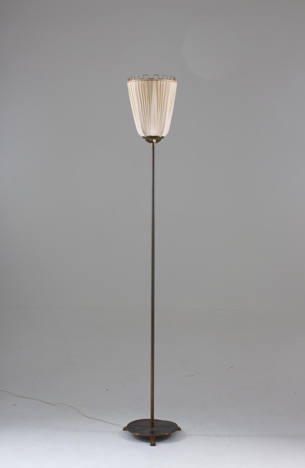 Rare floor lamp, most likely manufactured in Sweden, 1930s.

This floor lamp consists of a brass pole, supporting an up light fabric shade with brass ornaments.

Condition: Very good original condition. Original shade with light wear.