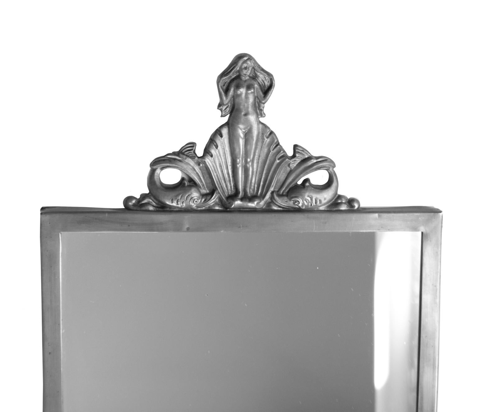 Miroir moderne suédois, Art déco, par Oscar Antonsson (1898-1960), en étain provenant d'Ystad Metall, 1931.
Estampillé Ystad Tenn XX. La couronne est décorée de la naissance de Vénus debout dans un coquillage, flanquée de deux Delphes. Mesures : 62