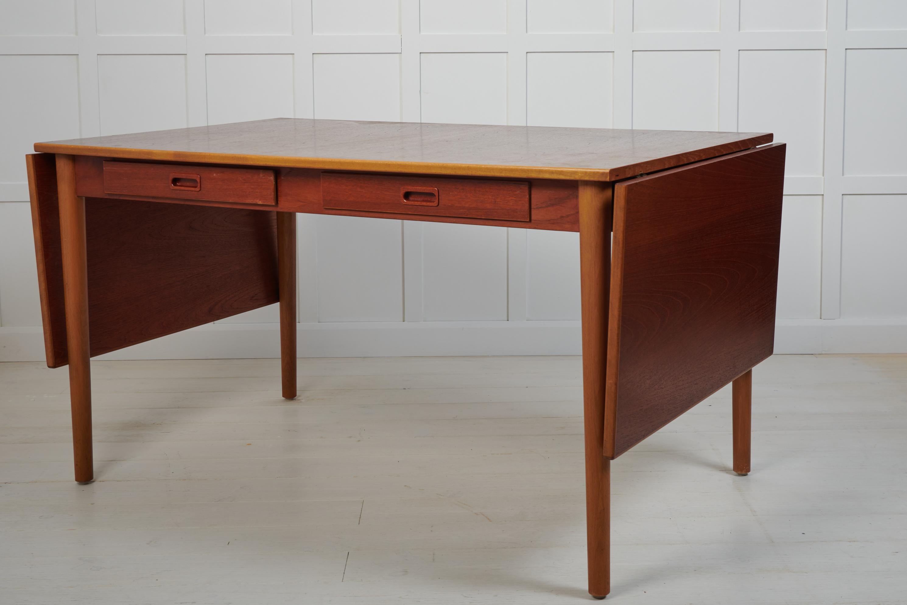 Scandinavian modern desk or dining table by Nils Jonsson for Troeds. Made in Sweden around 1960 with a table top in teak and beech leg frame.  The table has leaves on either short end and drawers in the apron. Good vintage condition with some