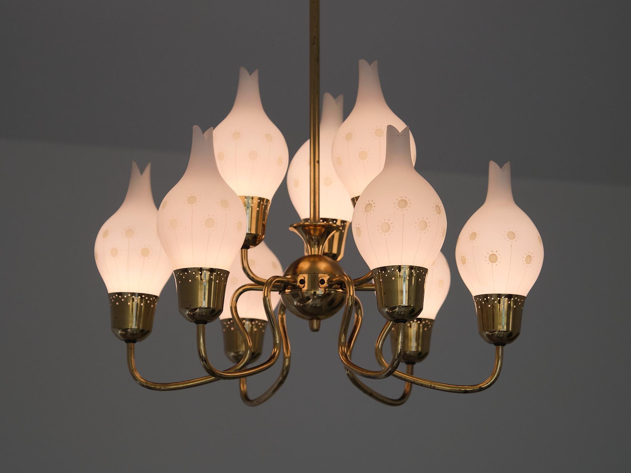 This spectacular nine-arm chandelier was designed and produced in Sweden in the 1950s.

The brass body features six downward-curving arms and three upward-curving arms, all attached to a sphere-shaped center. Each arm ends in a brass shade holder