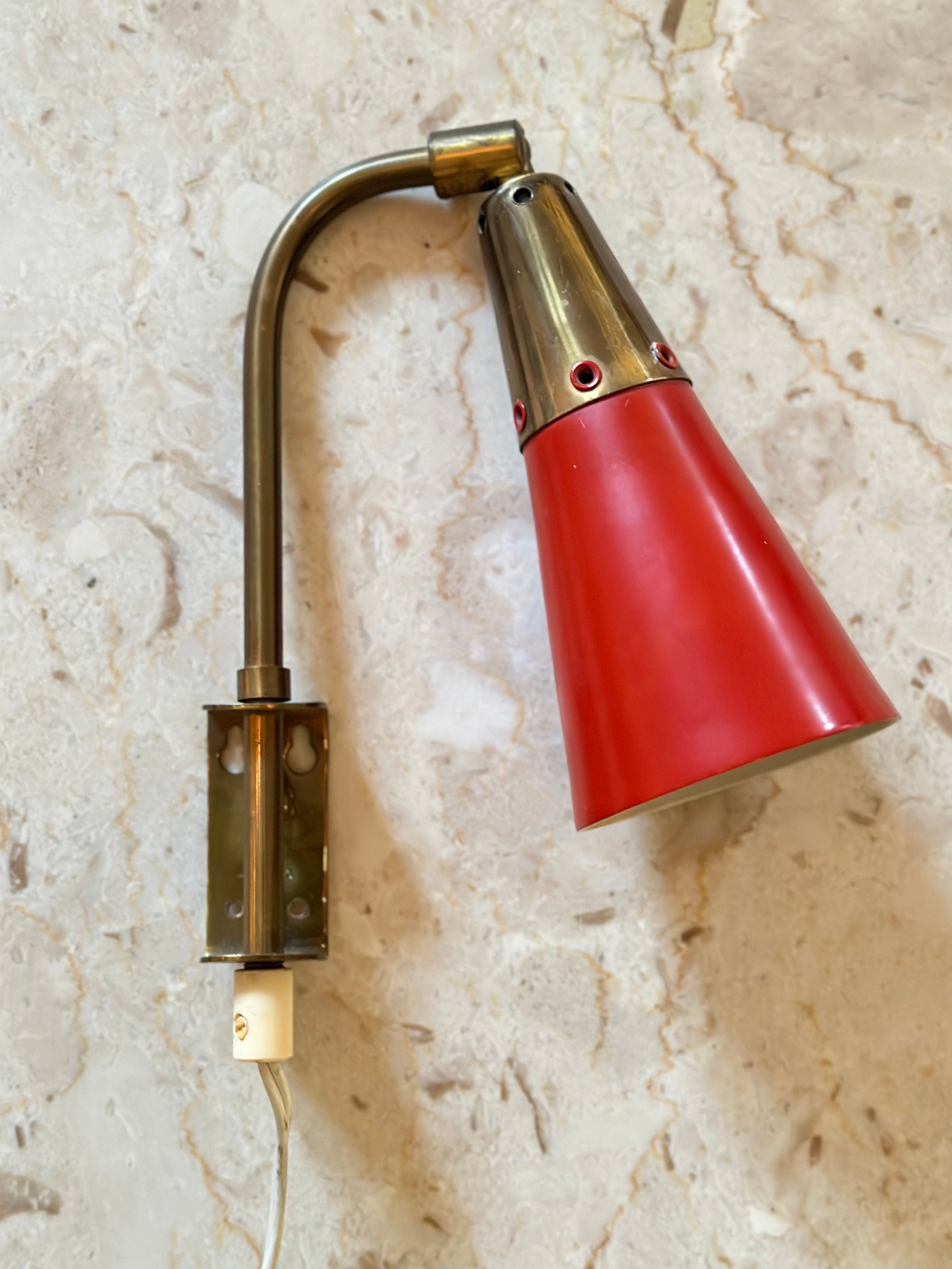 Pair of Swedish Modern adjustable brass wall lights with red lacquered shades and white reflective inside. Very decorative bedside lamps made by Upsala Armaturfabrik AB in the 1950s. In very good vintage condition with minimal wear to the lacquer.