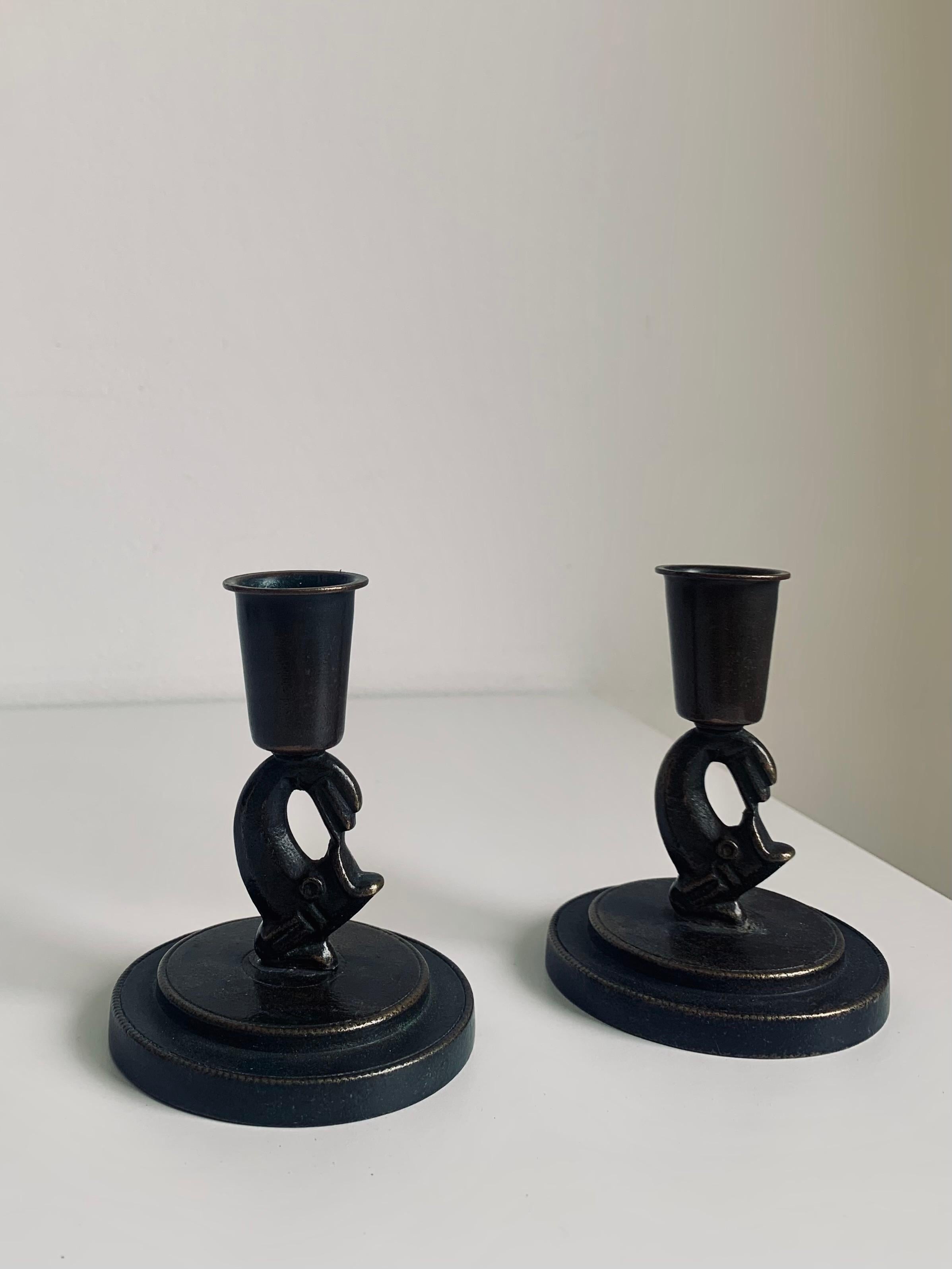 Dark patinated bronze candle sticks by Ystad Brons, ca 1930s. Likely designed by Carl-Einar Borgström as part of a desk set. 
Stylised fish holding the candle. Typical of Swedish Modern design. Nice dark brown patina. Stamped Ystad Brons Sweden.