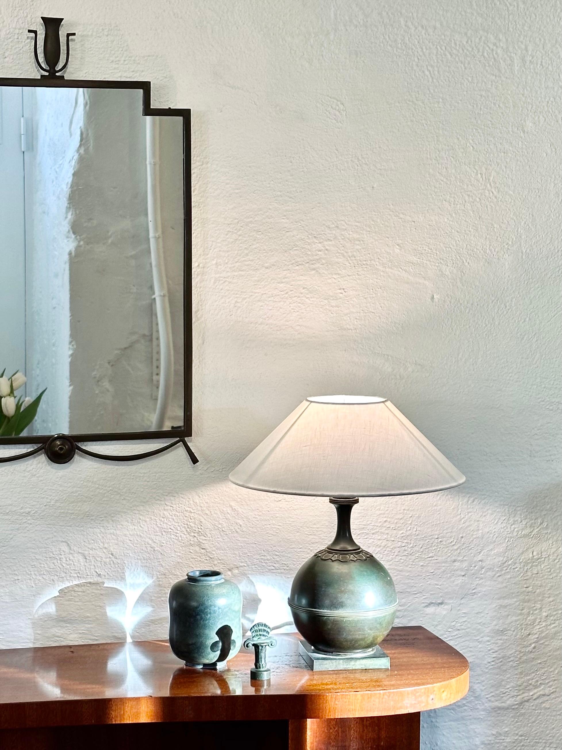 Swedish Modern patinated bronze table lamp in a nice spherical shape on a square base, likely designed by Jacob Ängman for GAB in the 1930s. Conical white linnen shade included. 


